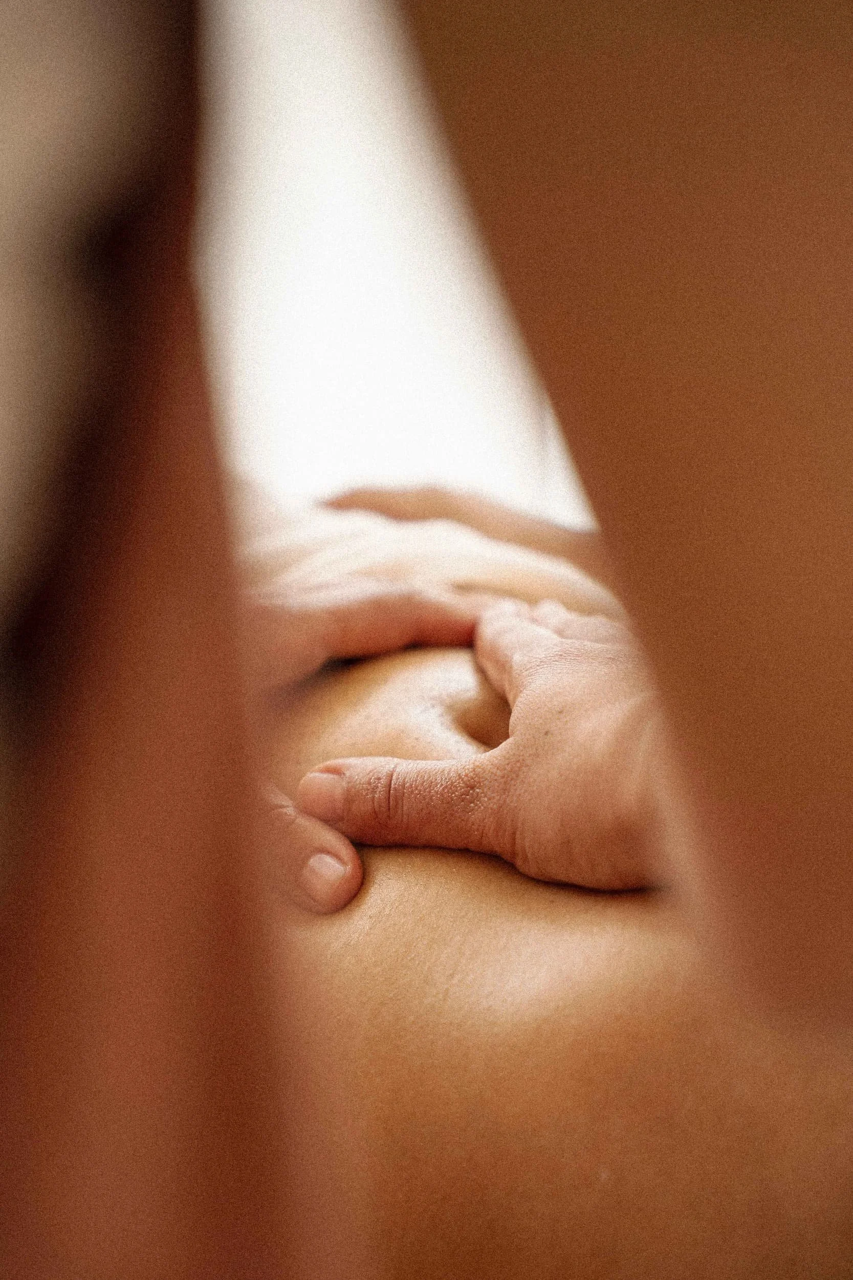 A close-up of a person’s hand pressing against their neck, with skin and fingers visible.