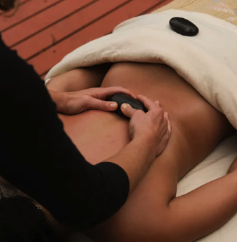 A person receiving a hot stone massage on their back in a spa setting.