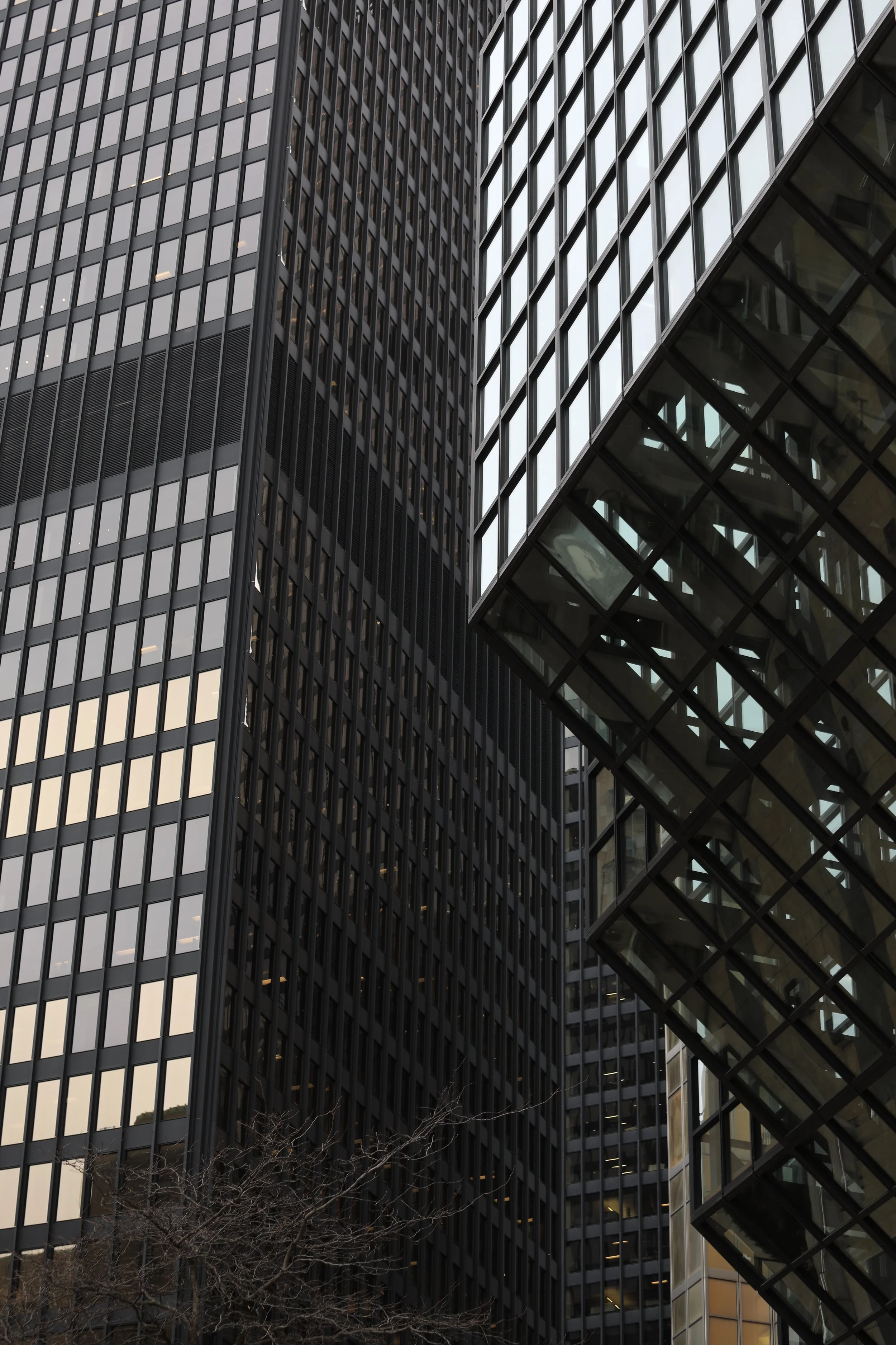 Tall modern office buildings with reflective glass windows and a glass skywalk connecting two structures.