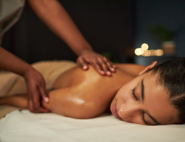 Woman receiving massage therapy on her back in a spa setting.