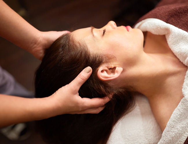 Woman receiving a massage in a spa or massage clinic, lying on her back with eyes closed at The Harrison Day Spa Cincinnati Ohio 