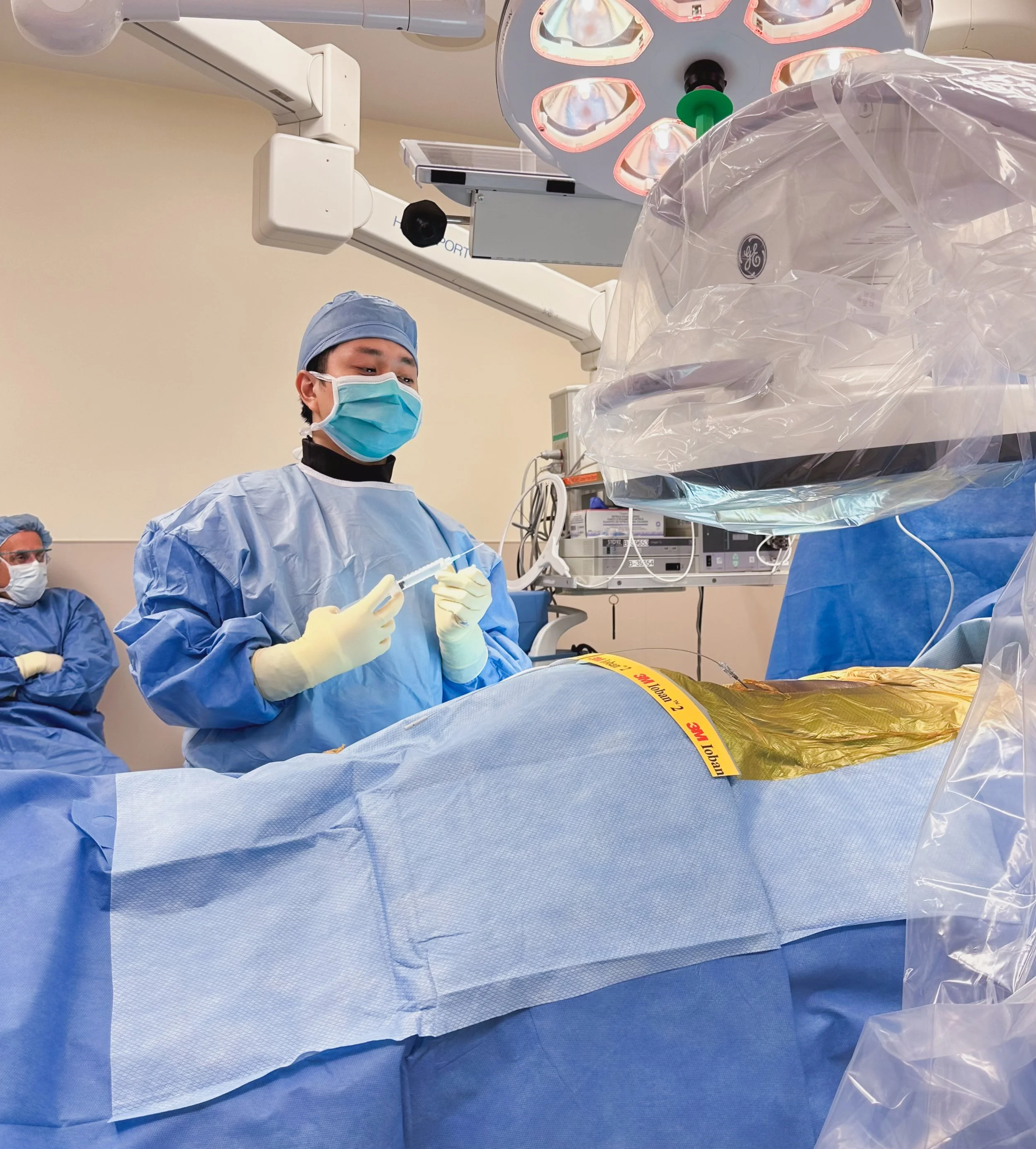 Dr. Isaac Lee, MD, interventional pain physician performing a procedure in an operating room