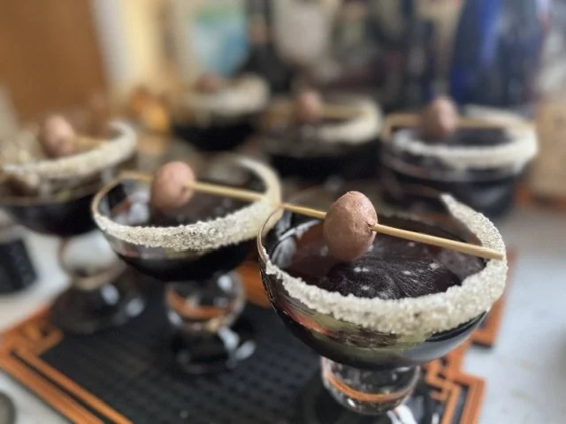 Multiple glasses of dark chocolate margaritas with salted rim and garnished with a chocolate-covered cherry on a skewere