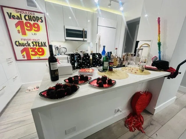 Kitchen counter with beverages, snacks, and party decorations, including a red heart-shaped balloon and colorful streamers.
