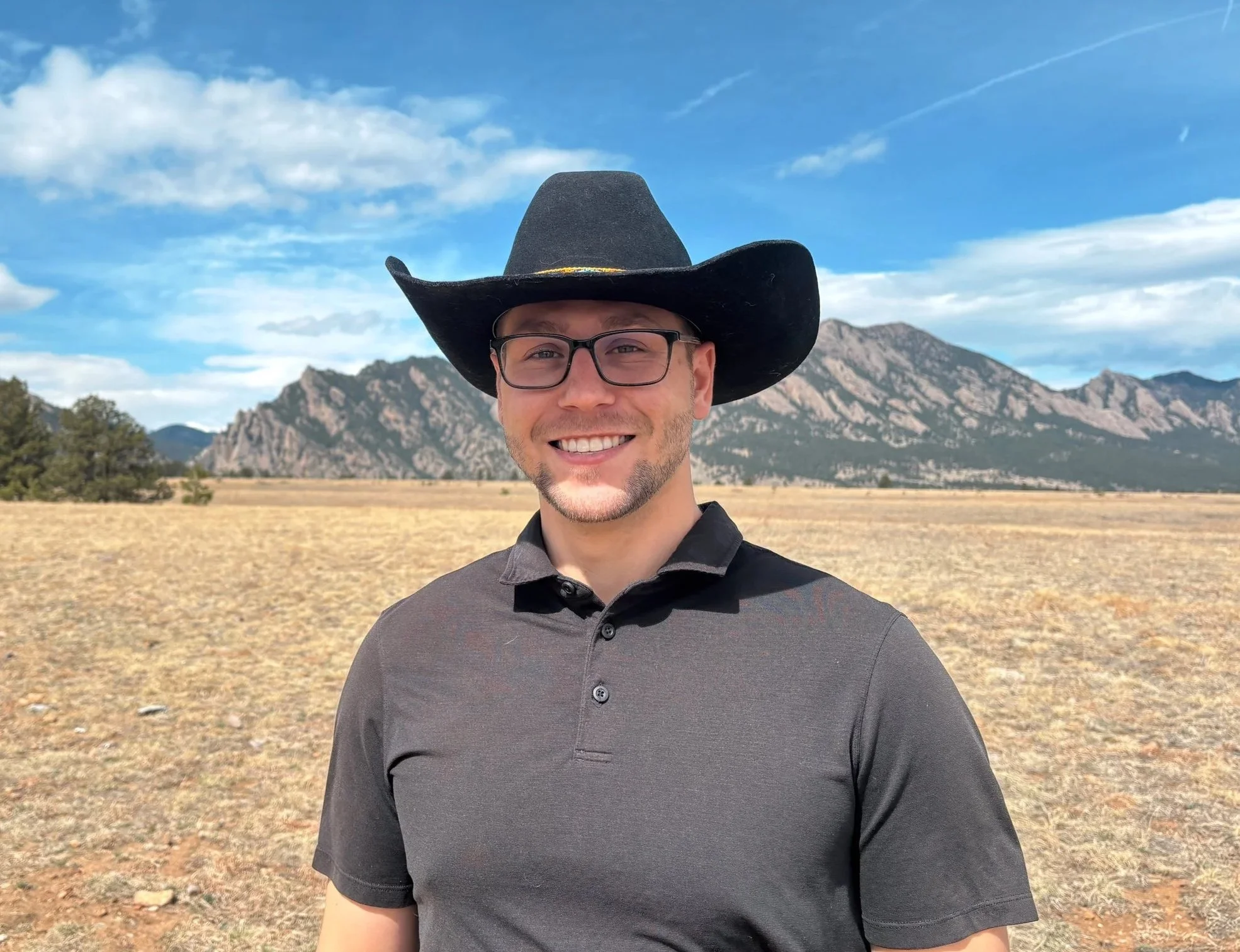 Dr. Ian, DC smiles in a cowboy hat while standing in front of the Flatiron Mountains near Westminster, CO