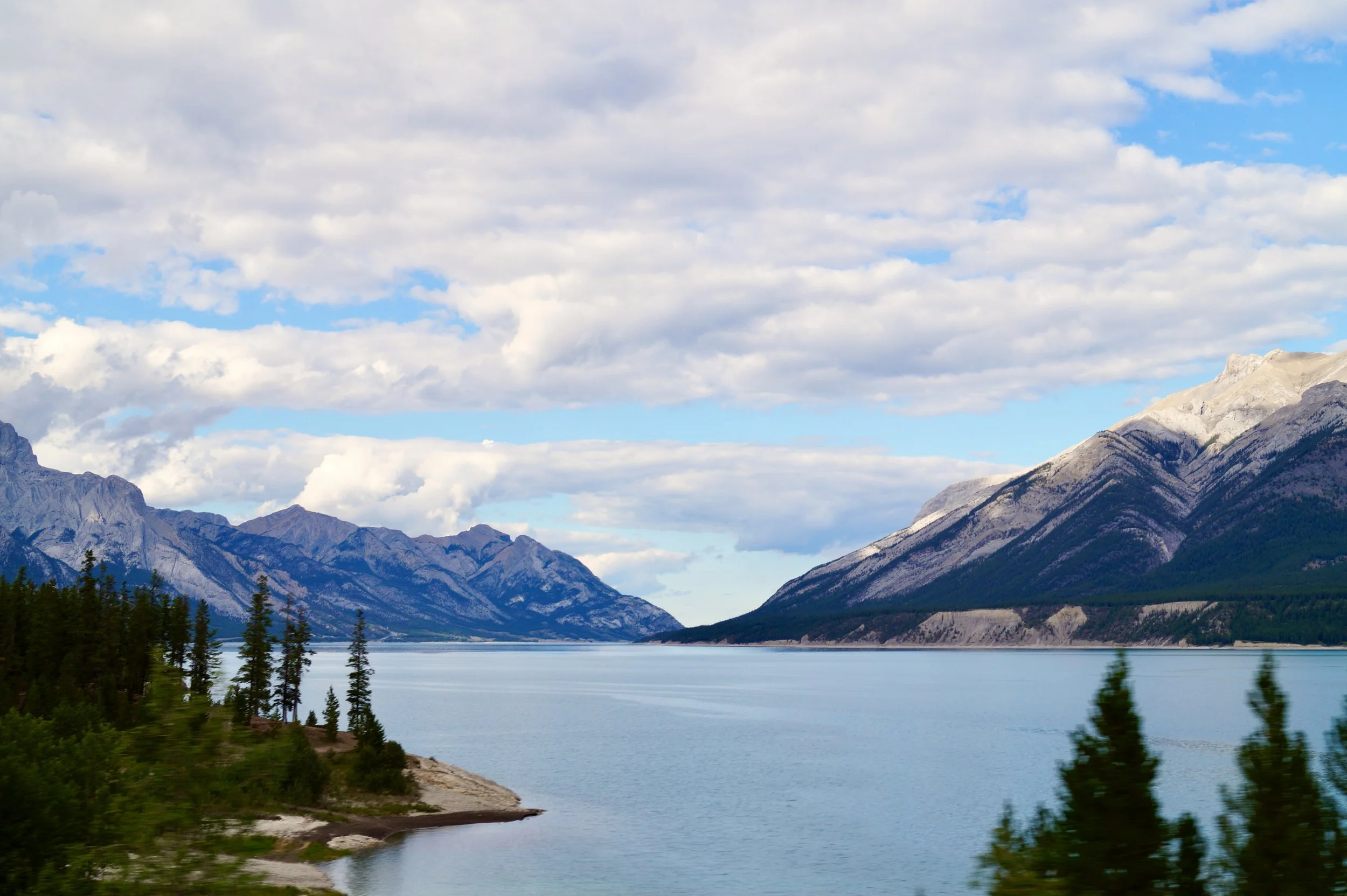Scenic view of a river or lake with mountainous landscape in the background, under a cloudy sky.