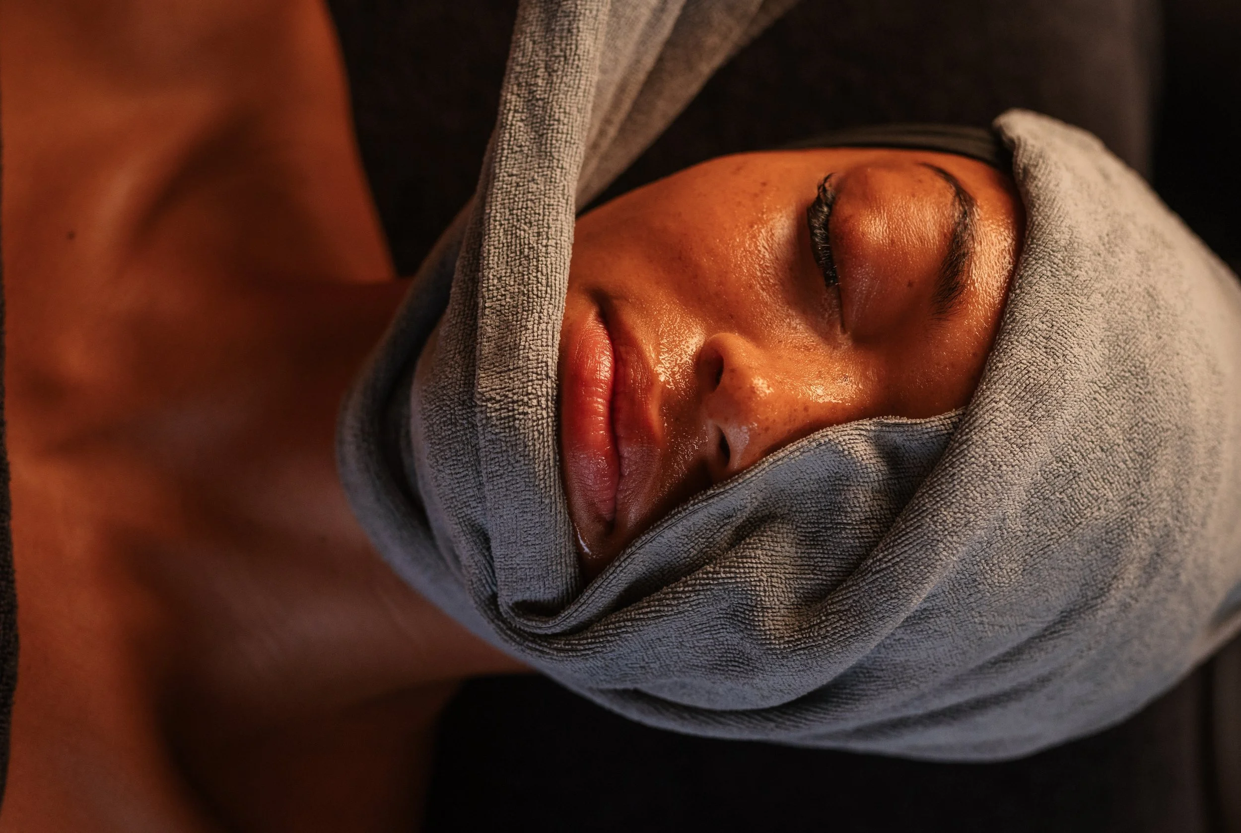 Close-up of a person receiving a warm towel wrap mid facial