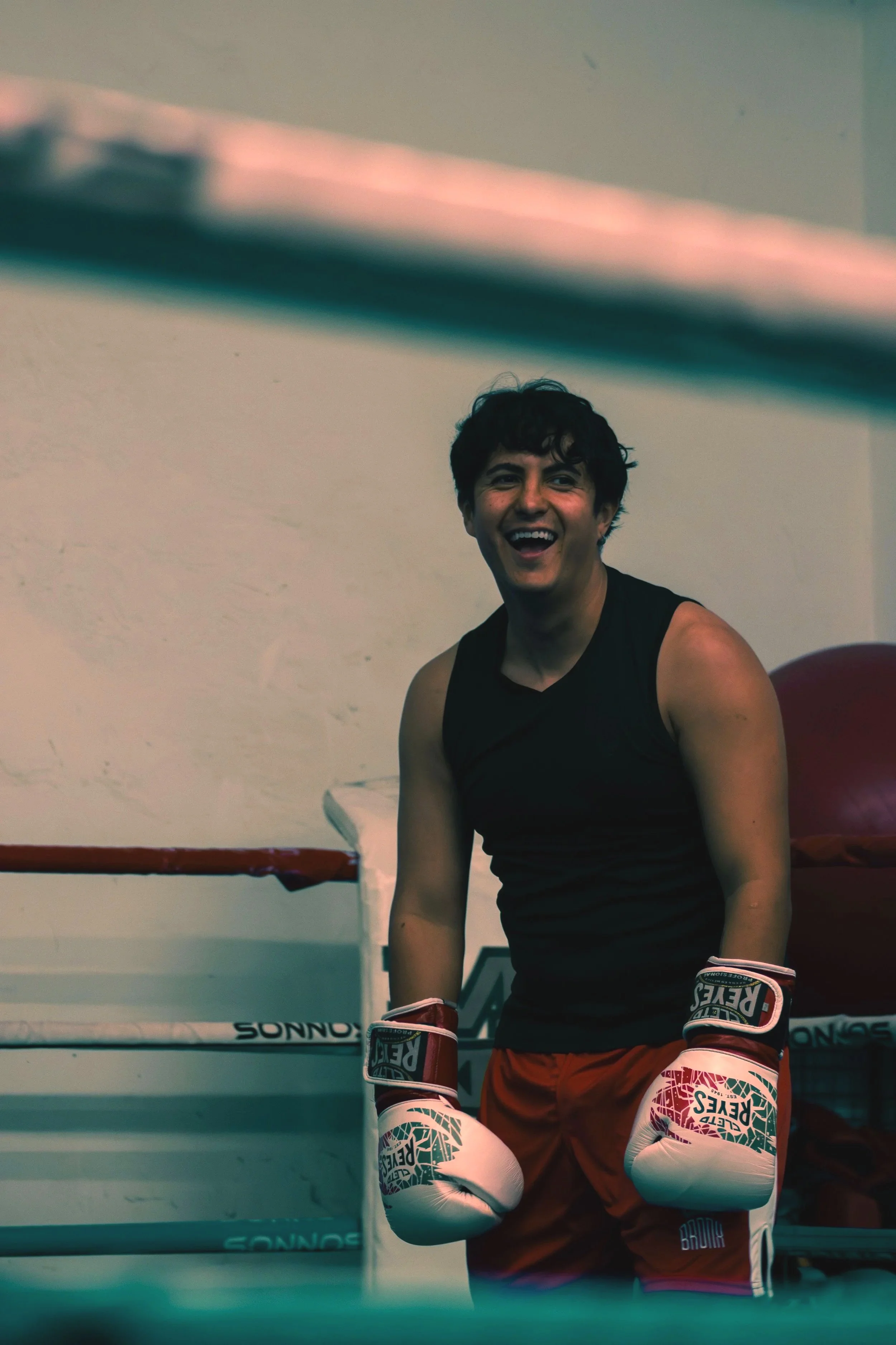 Young male boxer laughing and smiling during an active moment inside the boxing ring.