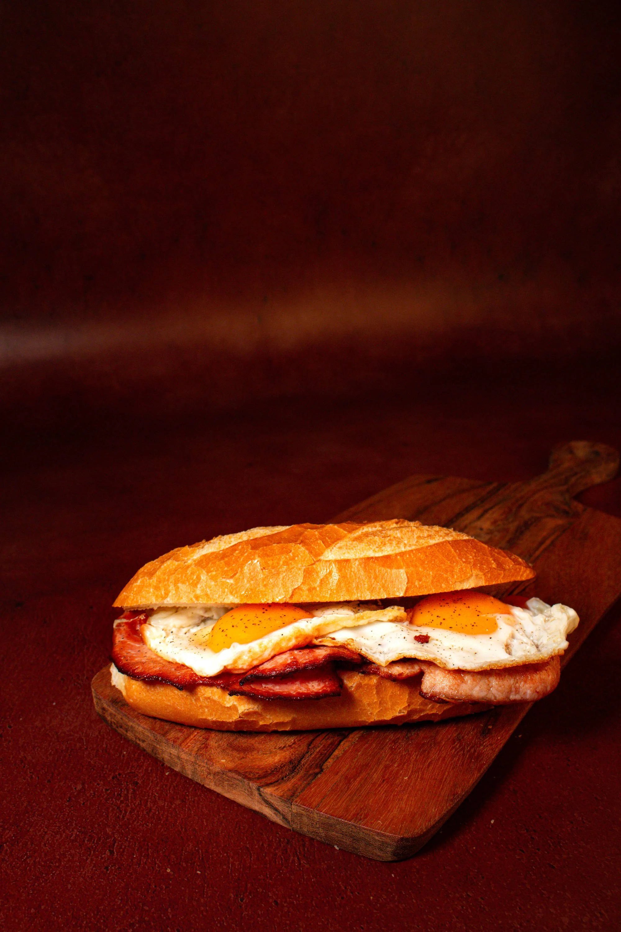 A breakfast sandwich roll with fried eggs and bacon