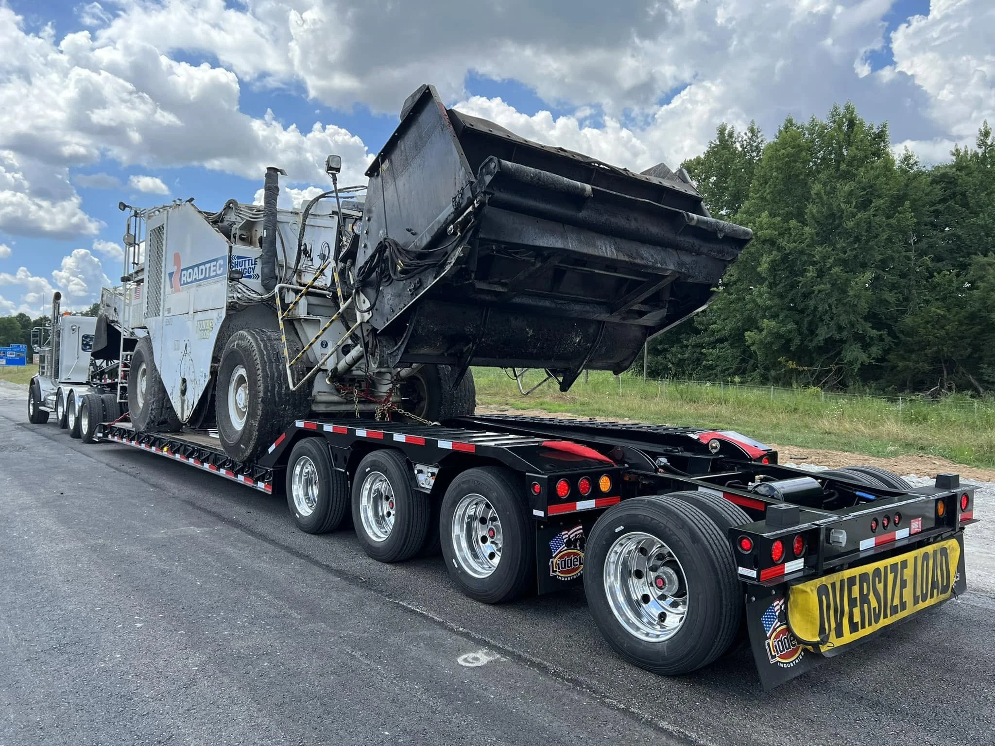 Large equipment secured on a multi-axle lowboy trailer.