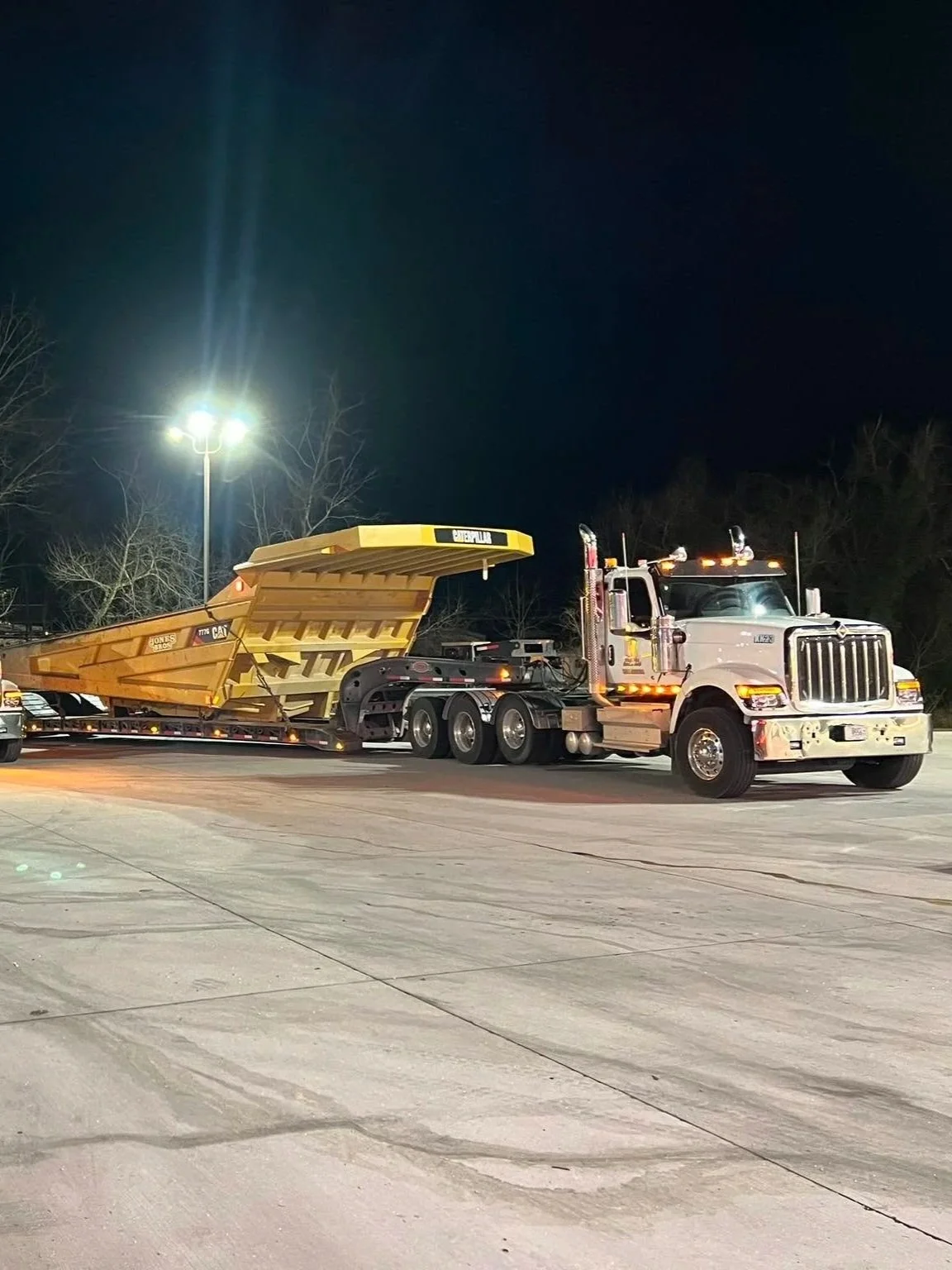 Heavy-haul trucks and trailers carrying large equipment at night.