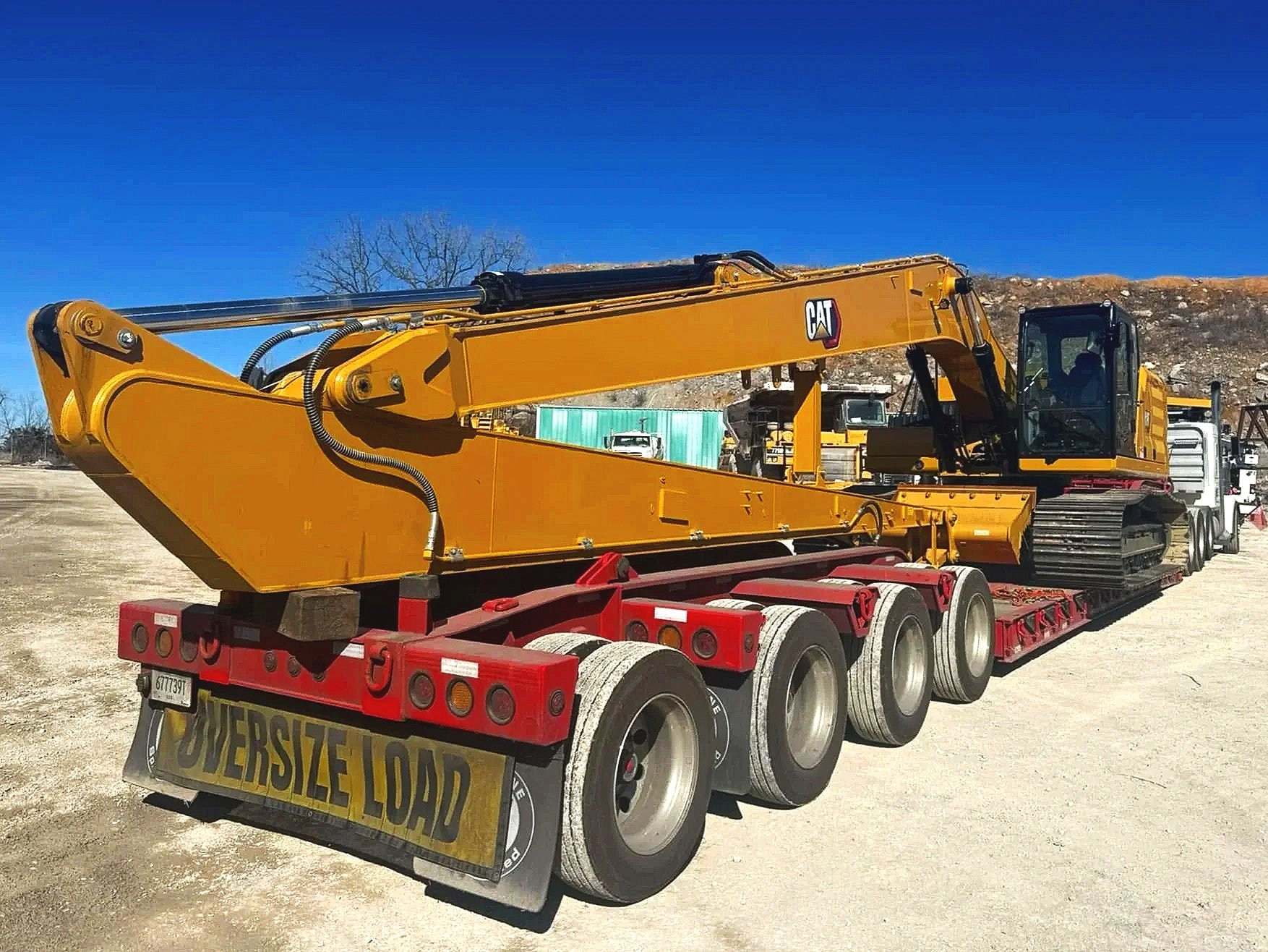 Heavy equipment loaded on a red multi-axle trailer.