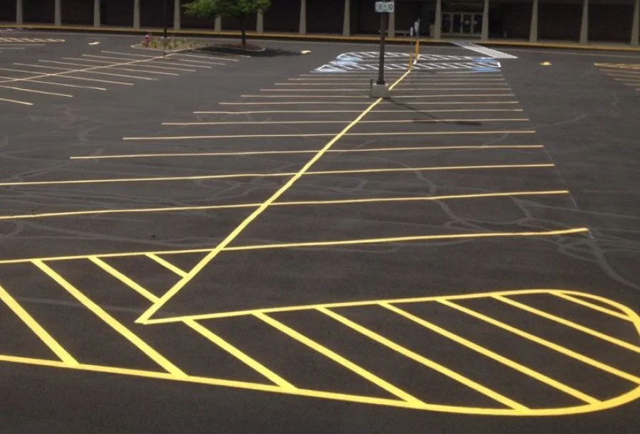 Empty parking lot with yellow painted lines and handicapped parking spaces in the background.
