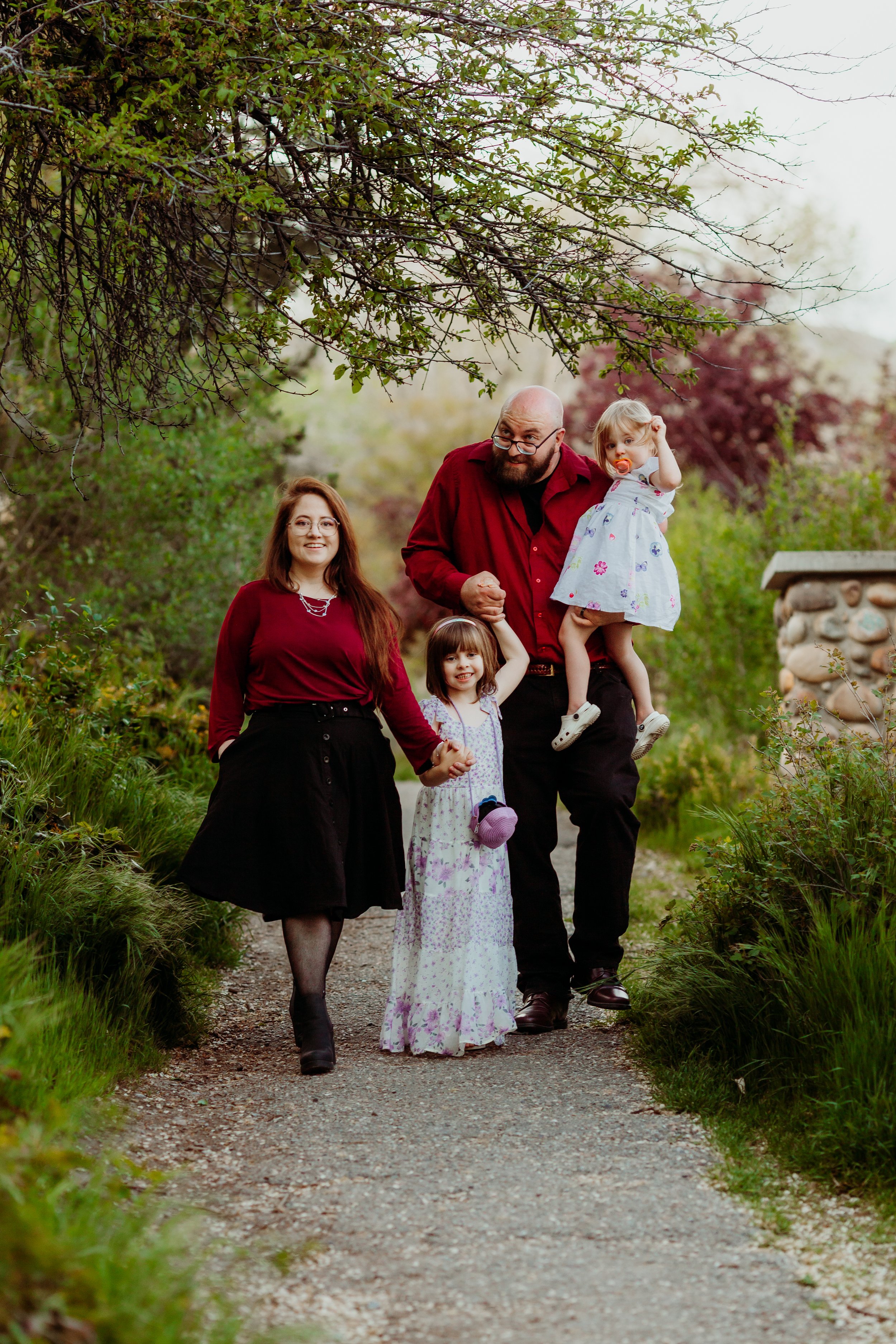 A family walking on a dirt path surrounded by greenery and trees.