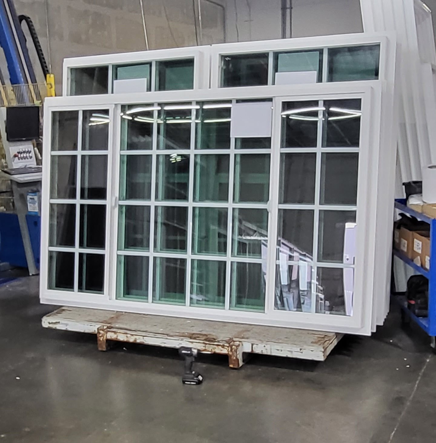Two white framed sliding windows stacked on top of each other in a warehouse setting.
