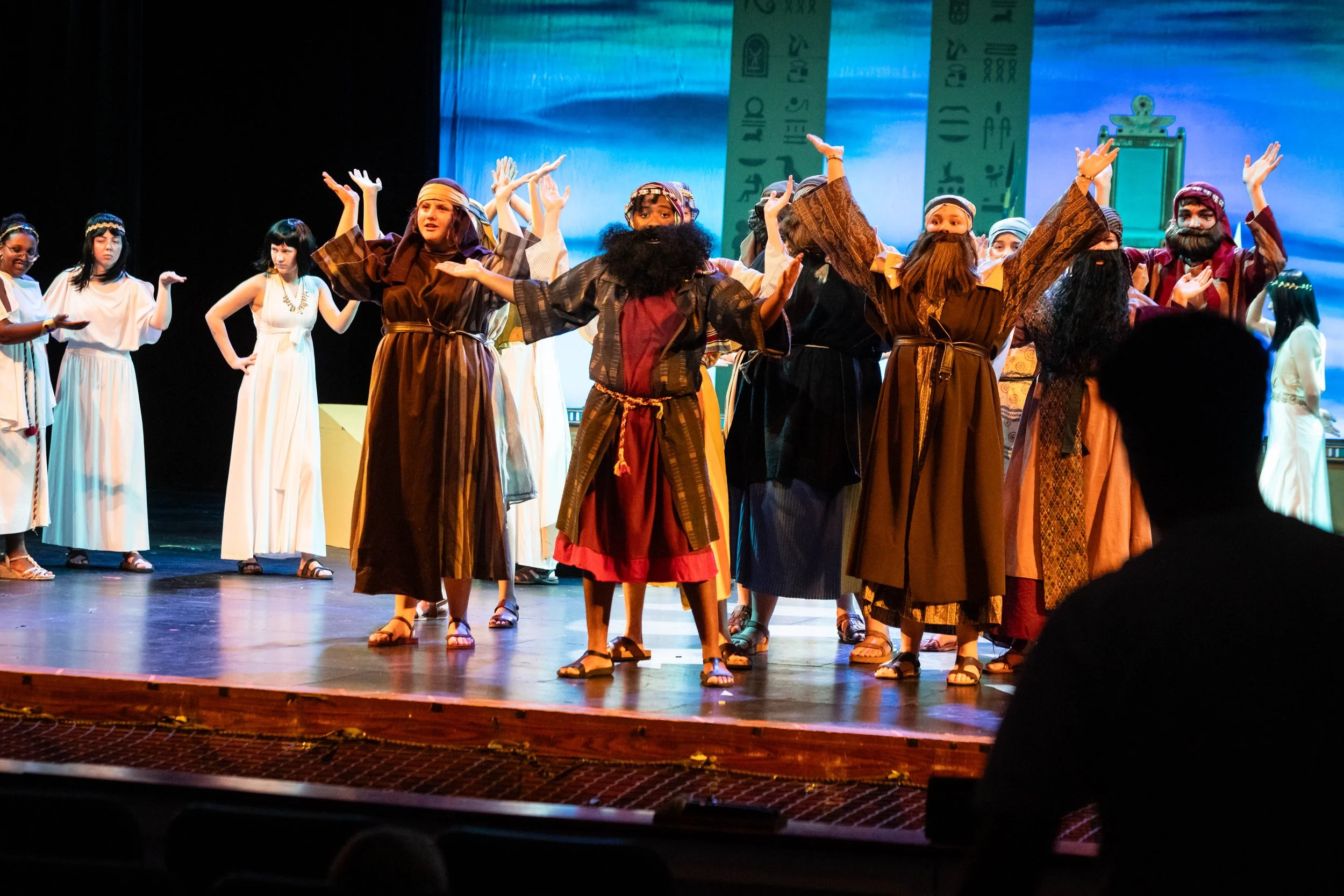 Actors dressed as biblical characters perform on stage during a play or musical with a backdrop resembling ancient Egypt or a similar setting.