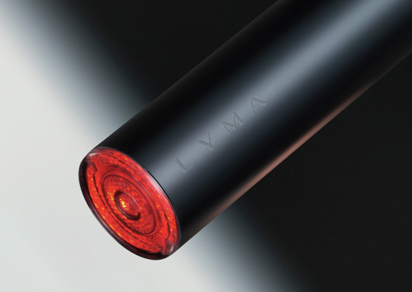 Close-up of a black cylindrical portable device with a red LED light at the end and the brand name 'LYMAY' engraved on its surface.