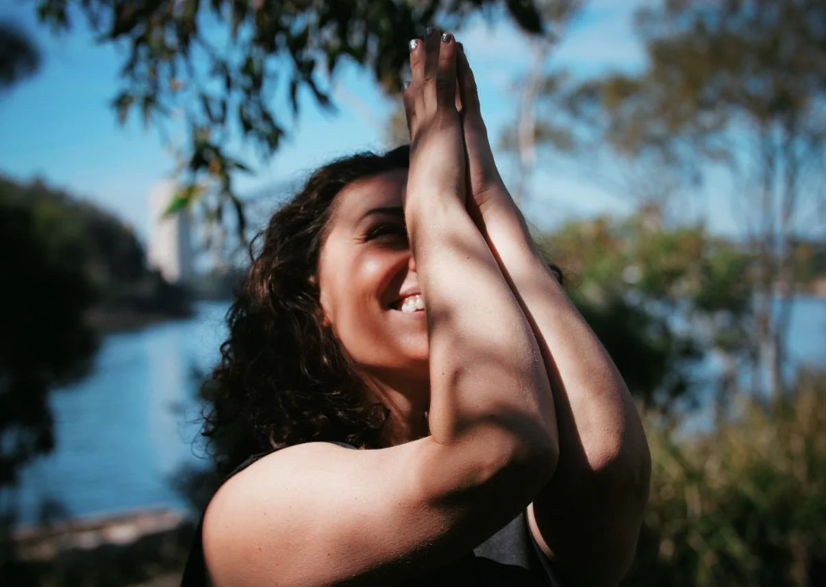 Christina, co-founder and yoga teacher at Flow Republic, practising outdoors in a prayer pose, reflecting her approach to movement, connection, and mindful practice.