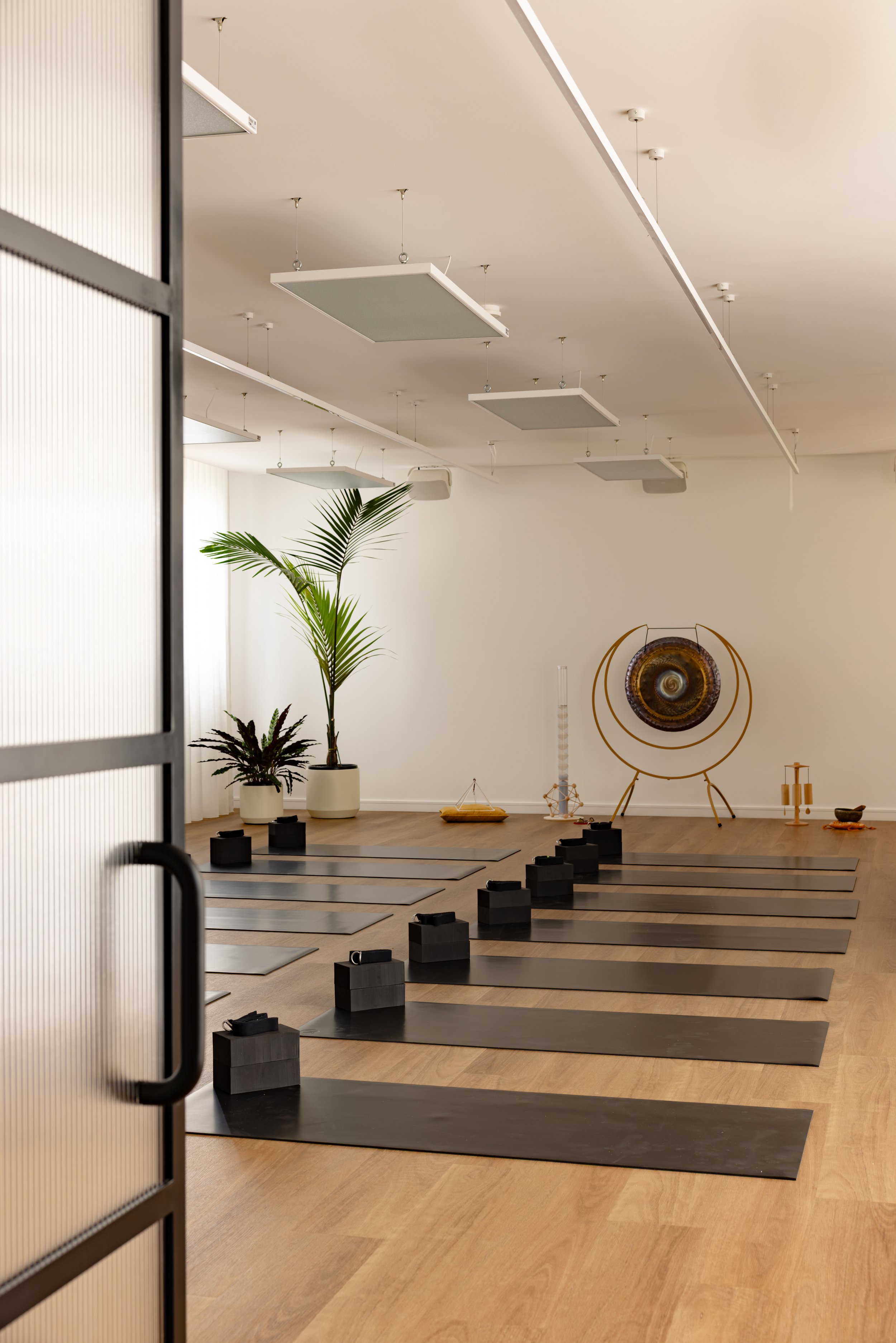 Light-filled main yoga practice space at Flow Republic, a premium yoga studio in Rozelle, Sydney, featuring modern yoga mats, props, sound healing instruments and calming interiors.