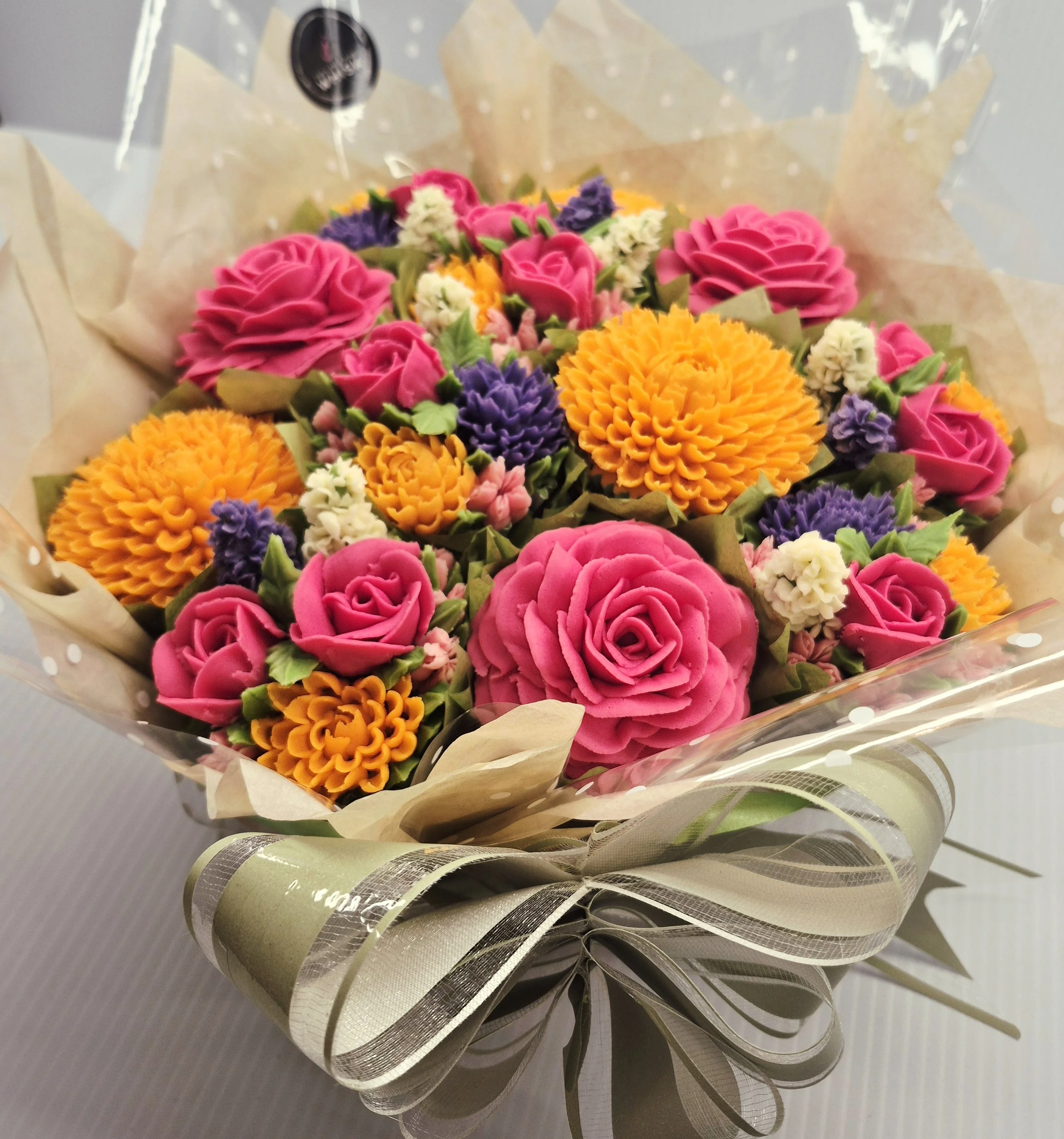 Colorful bouquet of pink, orange, purple, and white flowers wrapped in decorative paper.