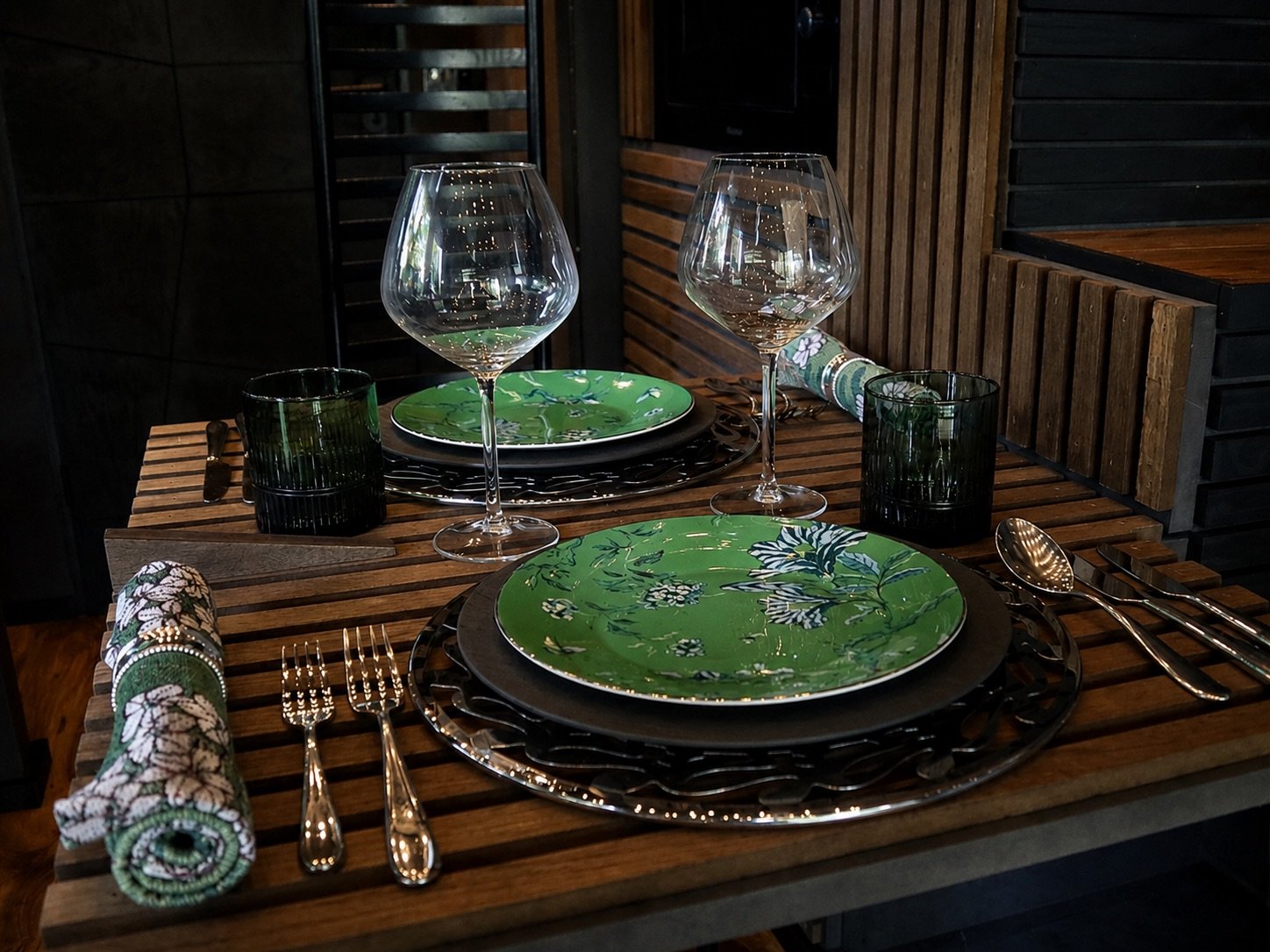 Bespoke dining table inside NOCTURNE, carefully set with green tableware, glassware and sculptural natural details.
