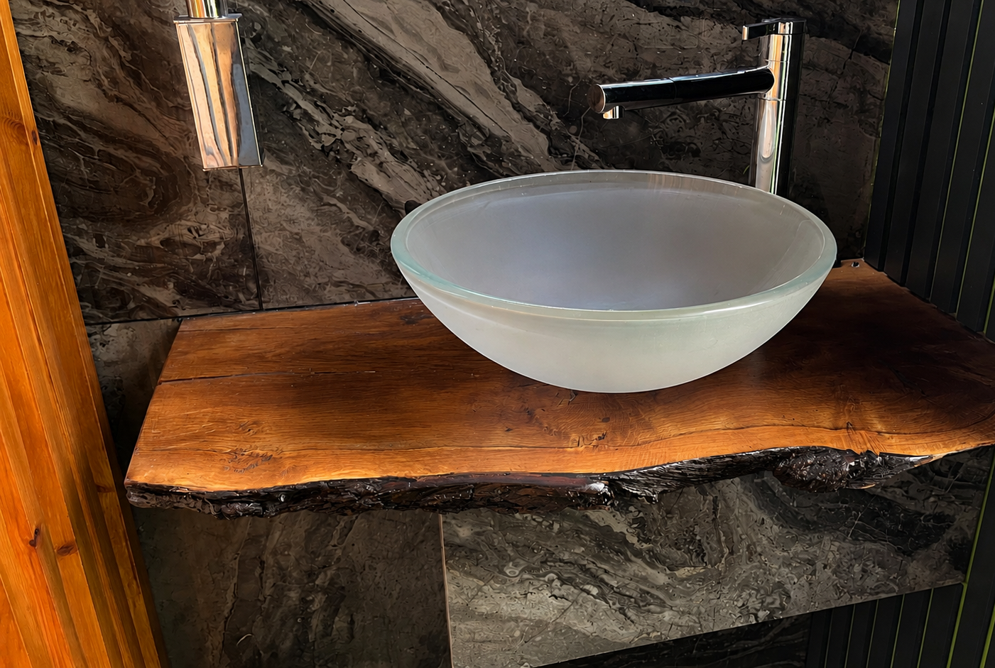 Close-up of the glass basin and black tap on a live-edge walnut shelf in the PLUVIA outdoor shower room