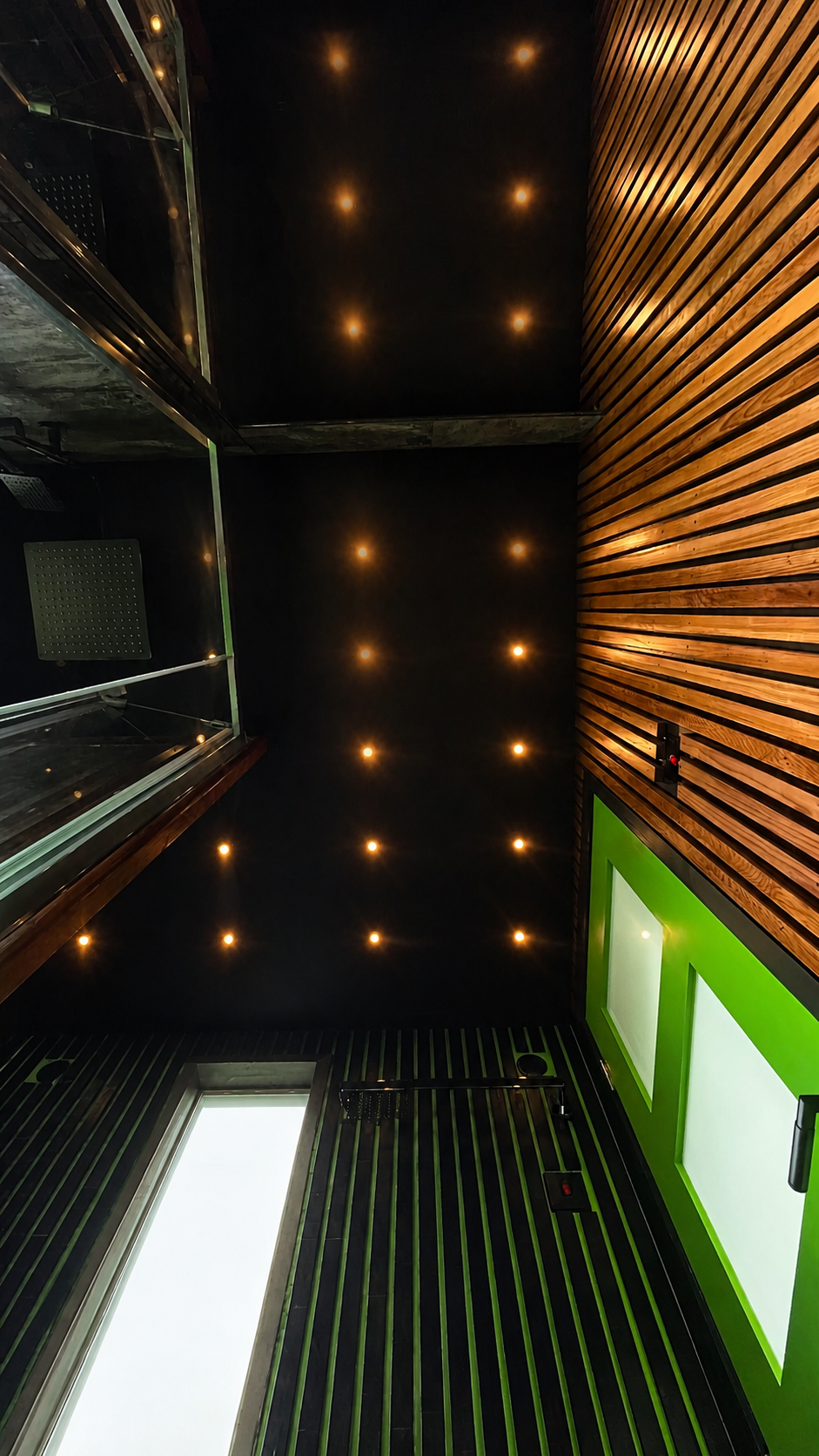 Warm architectural ceiling lights across real cedar cladding inside the PLUVIA luxury outdoor shower room
