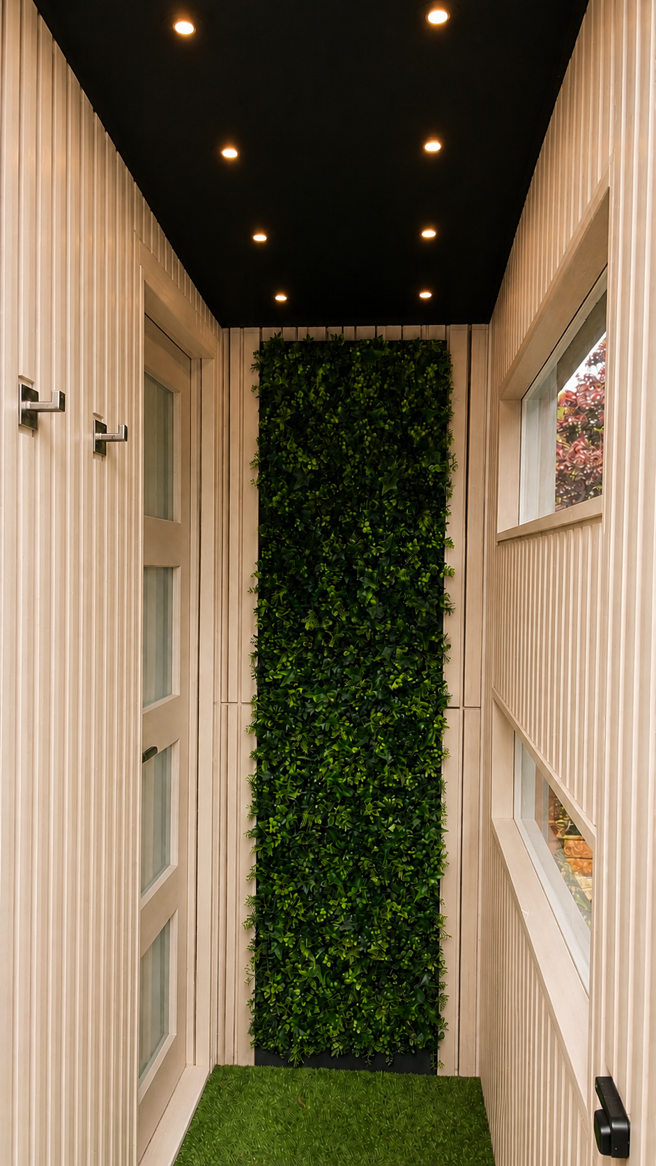 Living wall framed by warm off-white timber within the private entrance to the PLUVIA COASTAL outdoor shower room