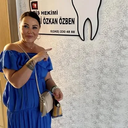 A woman in a blue dress pointing at a dental clinic sign on the wall.