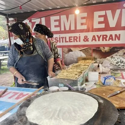 Two women preparing traditional Turkish flatbread at a food stall.