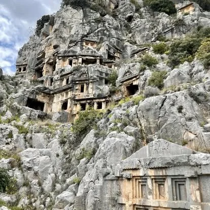 Ancient rock-cut tombs and caves carved into a mountainside in Turkey.