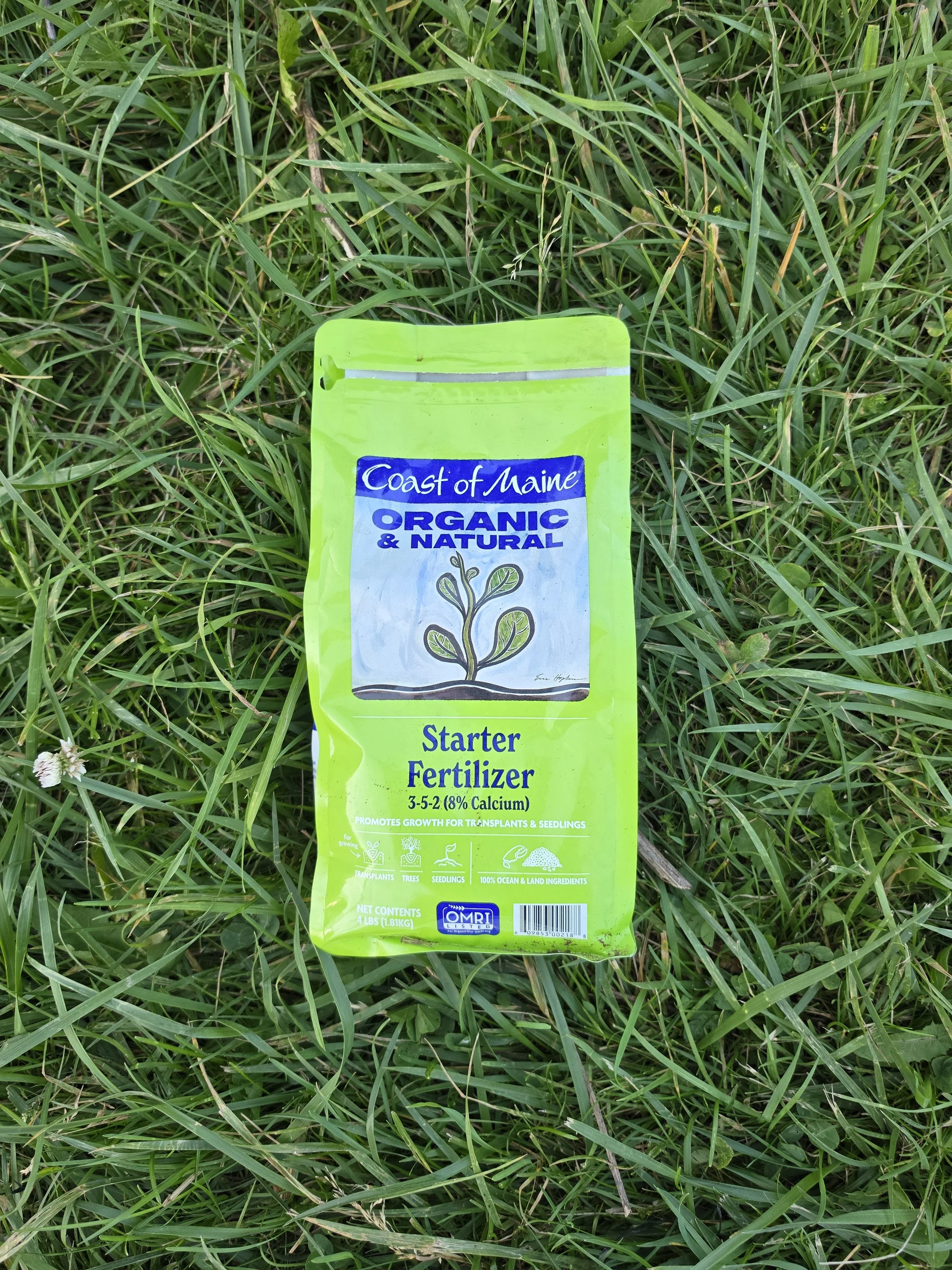 Packet of starter fertilizer lying on green grass.