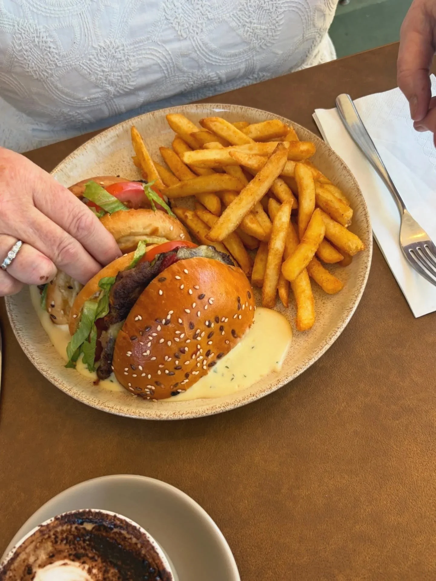 Beef burger with tomato, lettuce, relish, dijon mustard and aged cheddar cut in half and dunked in a cheesey creamy sauce with crispy chips on the side