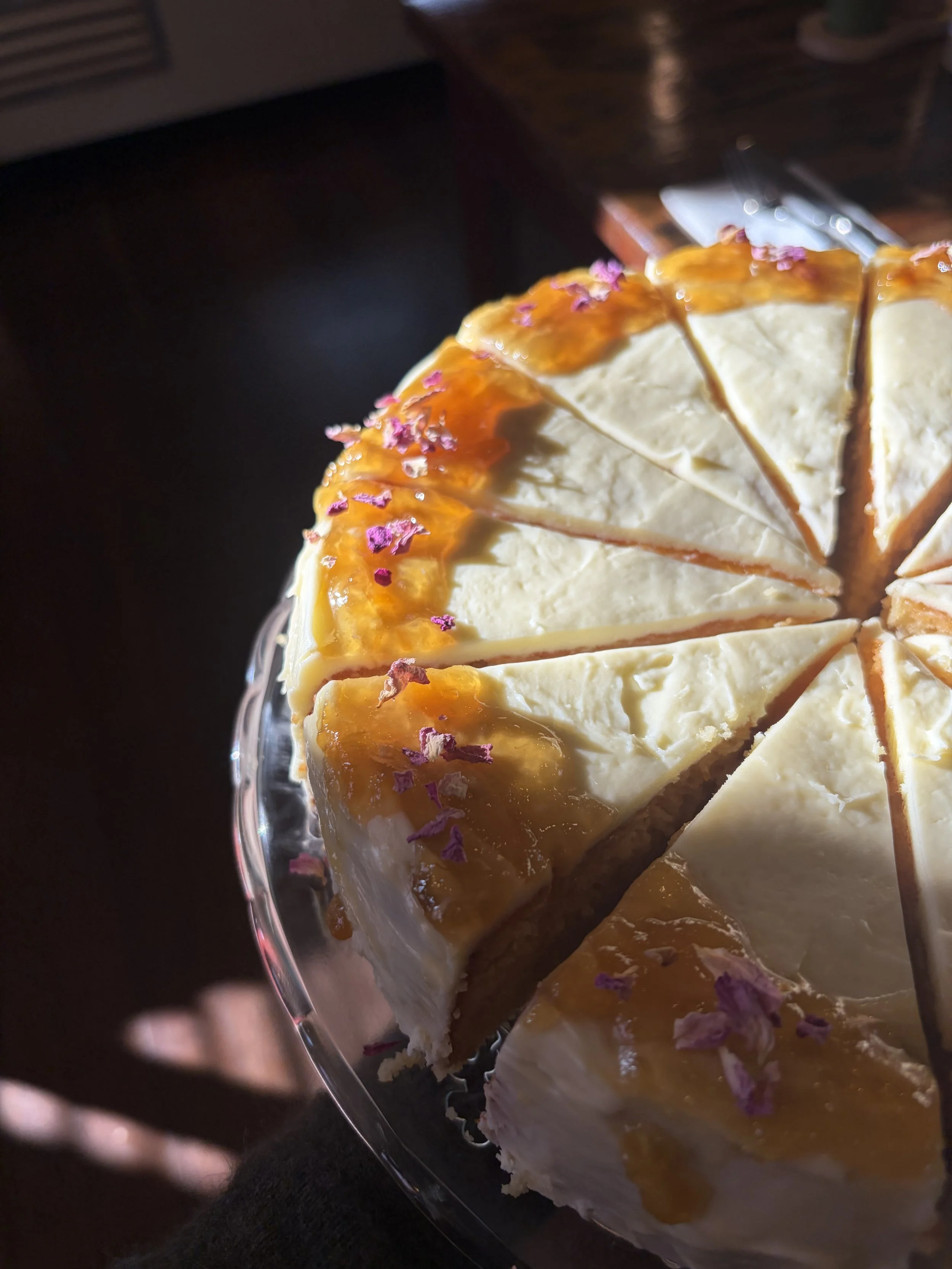 Close-up of a partially sliced flourless citrus cake decorated with a house made lemon marmalade, sitting on a glass cake stand.