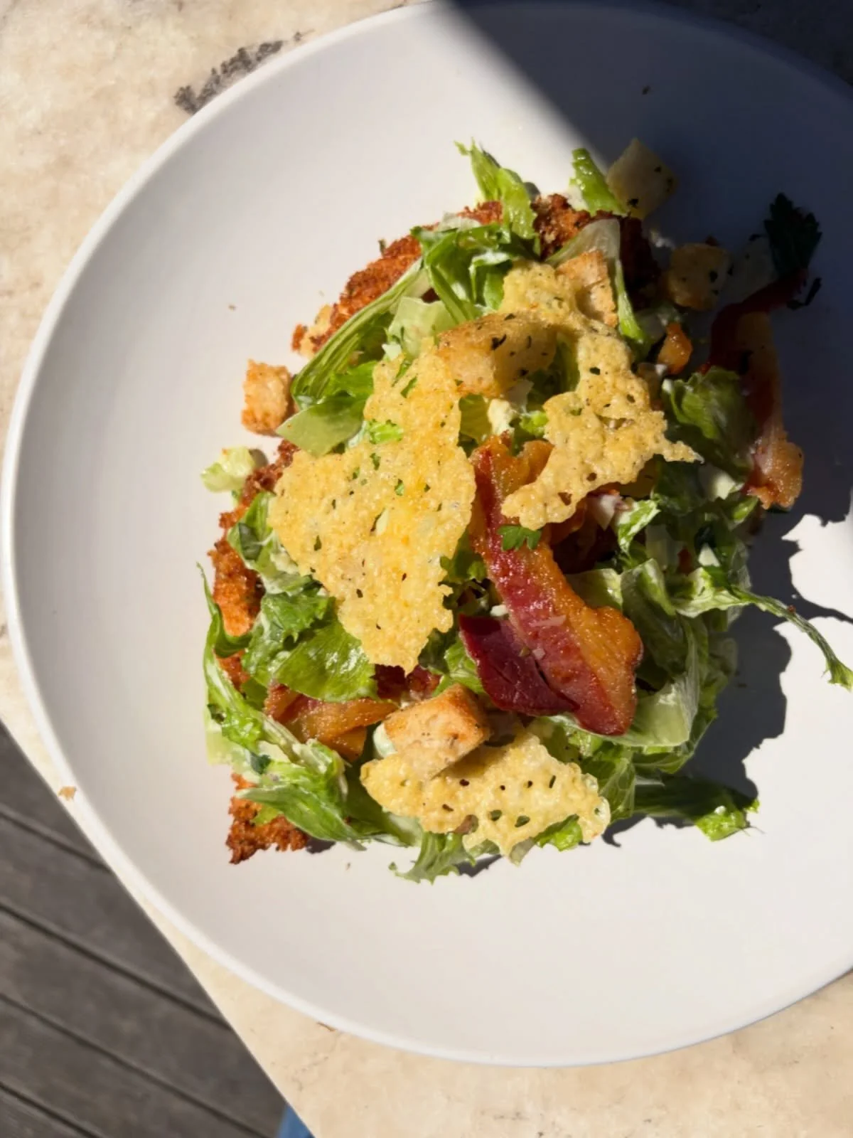 Chicken Schnitzel topped with a caesar salad of crispy bacon, chopped cos lettuce, croutons, parmesan and an anchovy dressing