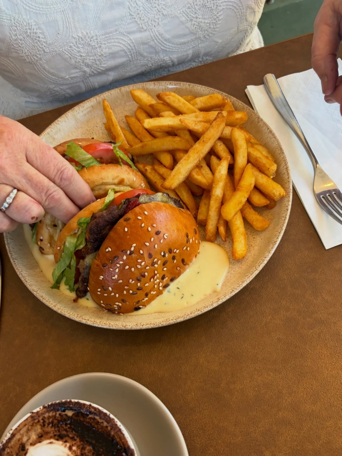 Beef burger with tomato, lettuce, relish, dijon mustard and aged cheddar cut in half and dunked in a cheesey creamy sauce with crispy chips on the side