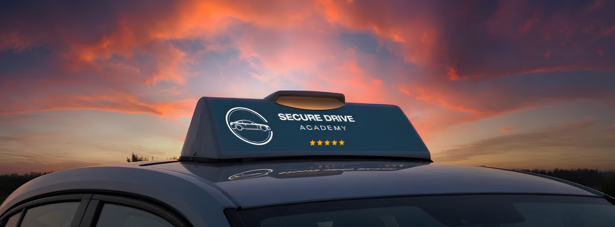 A close-up of a driving school car's roof with a sign that reads 'Secure Drive Academy' along with a graphic of a car and five stars, set against a colorful sunset sky.