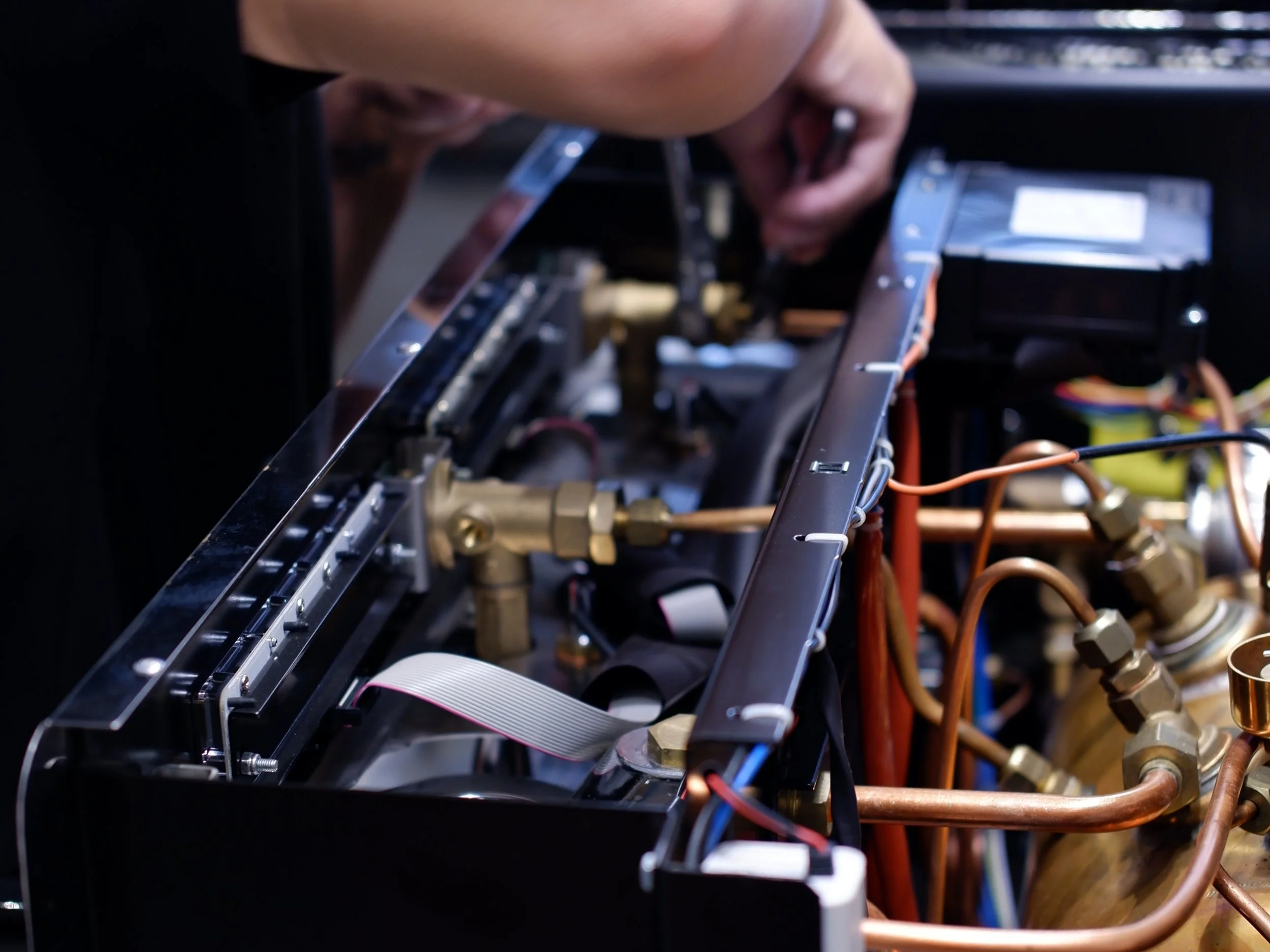 Close-up of electronic components and wiring inside a device or machinery, with metallic and copper parts and circuit boards.