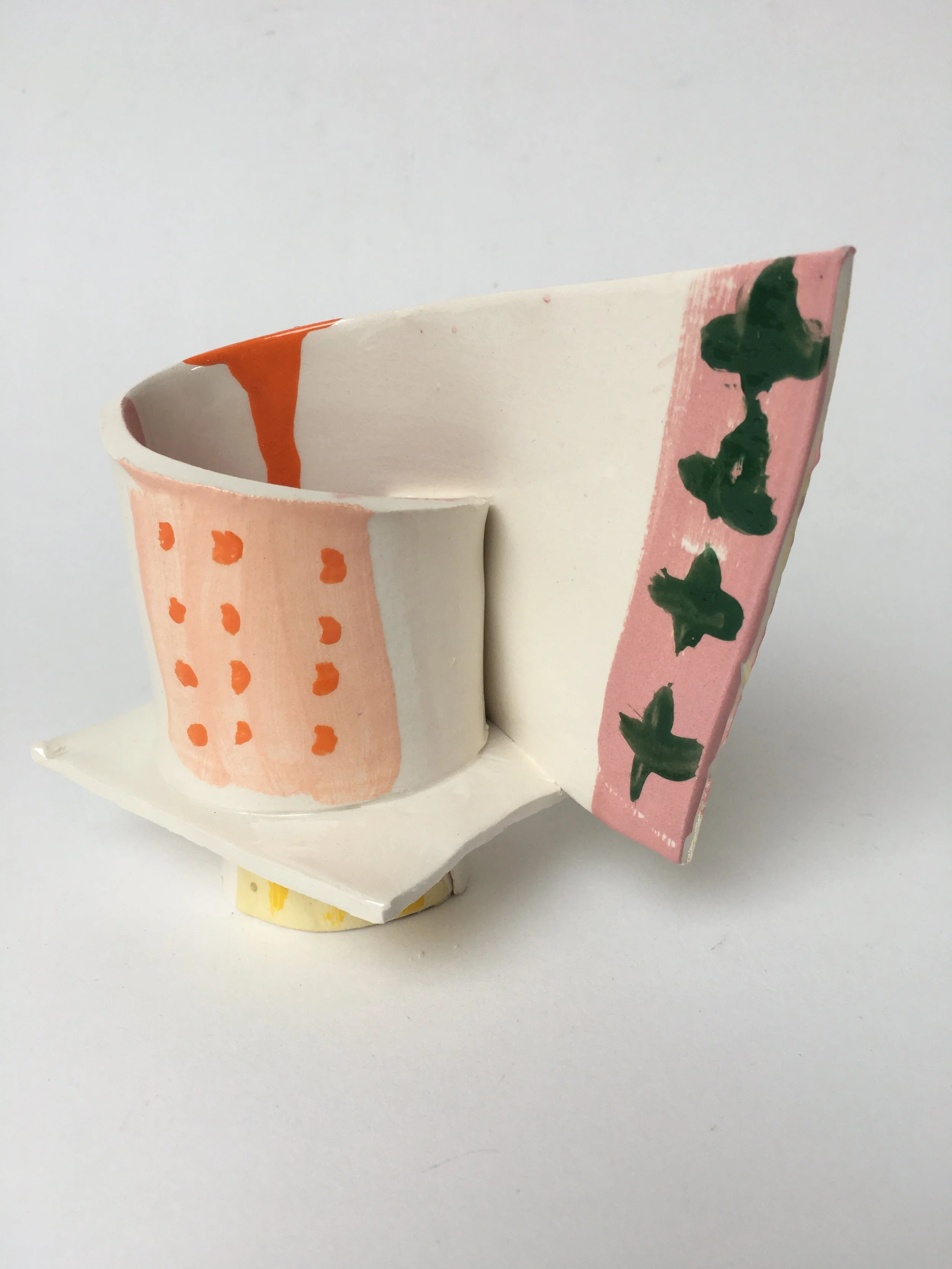 A painted ceramic or pottery piece with pink, white, orange, and green colors, featuring abstract patterns and designs.