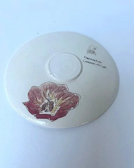 A white plate with a drawing of a flower and some handwritten notes on the back side.