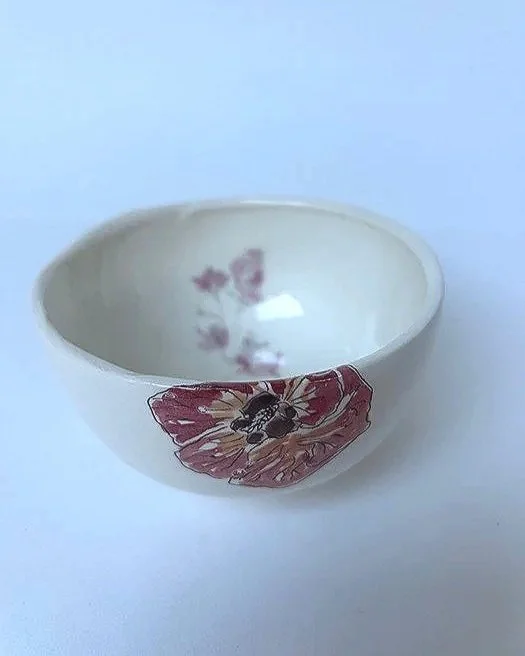 A white ceramic bowl with pink floral and butterflies design on the exterior, viewed from above against a plain background.