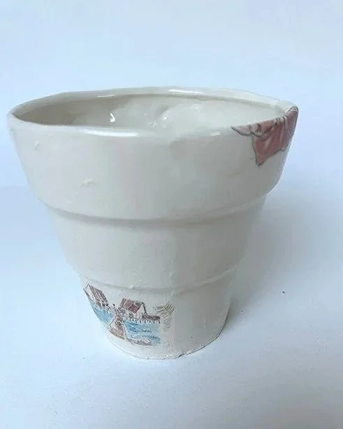 Stacked ceramic bowls with a beach scene and floral design, with the top bowl having a small chip on the rim.