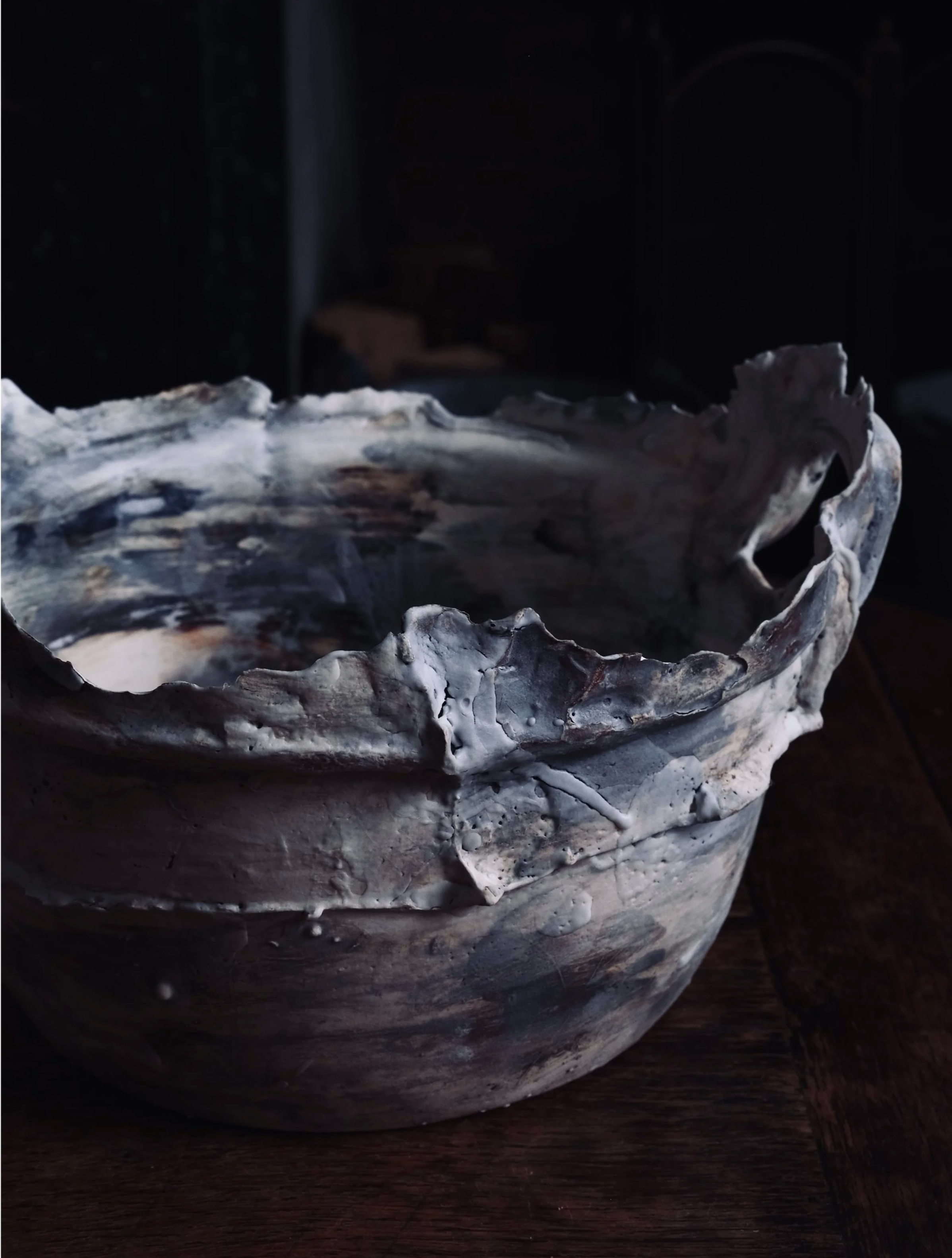 A ceramic bowl with a marbled white and gray design sits on a dark wooden surface.