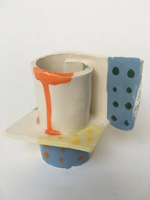 Colorful ceramic mug with drip design, polka dots, and geometric patterns on a white background.