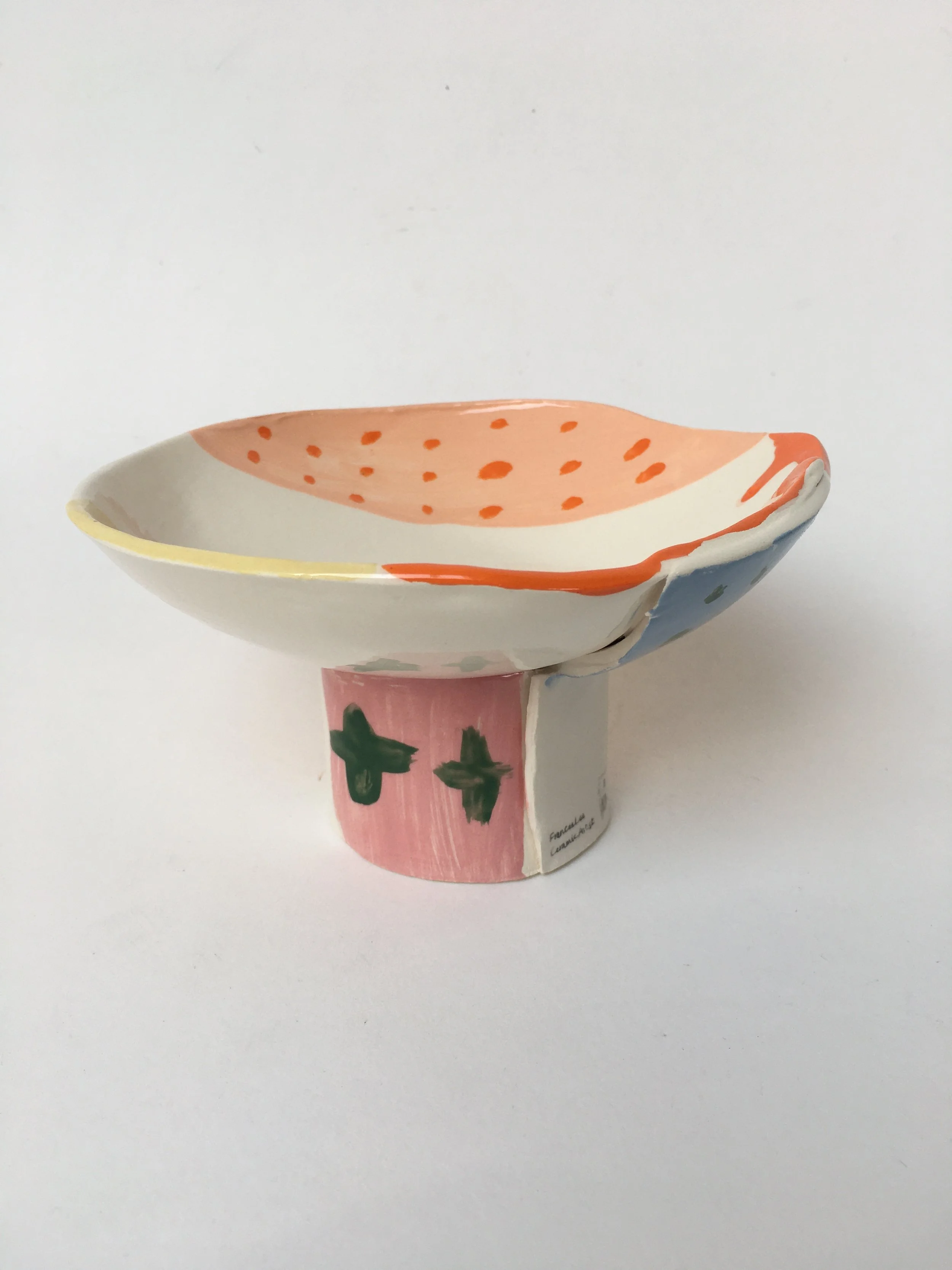 Handmade ceramic bowl with painted strawberry pattern on the inside and painted green leaves on the outside, placed on a white background.