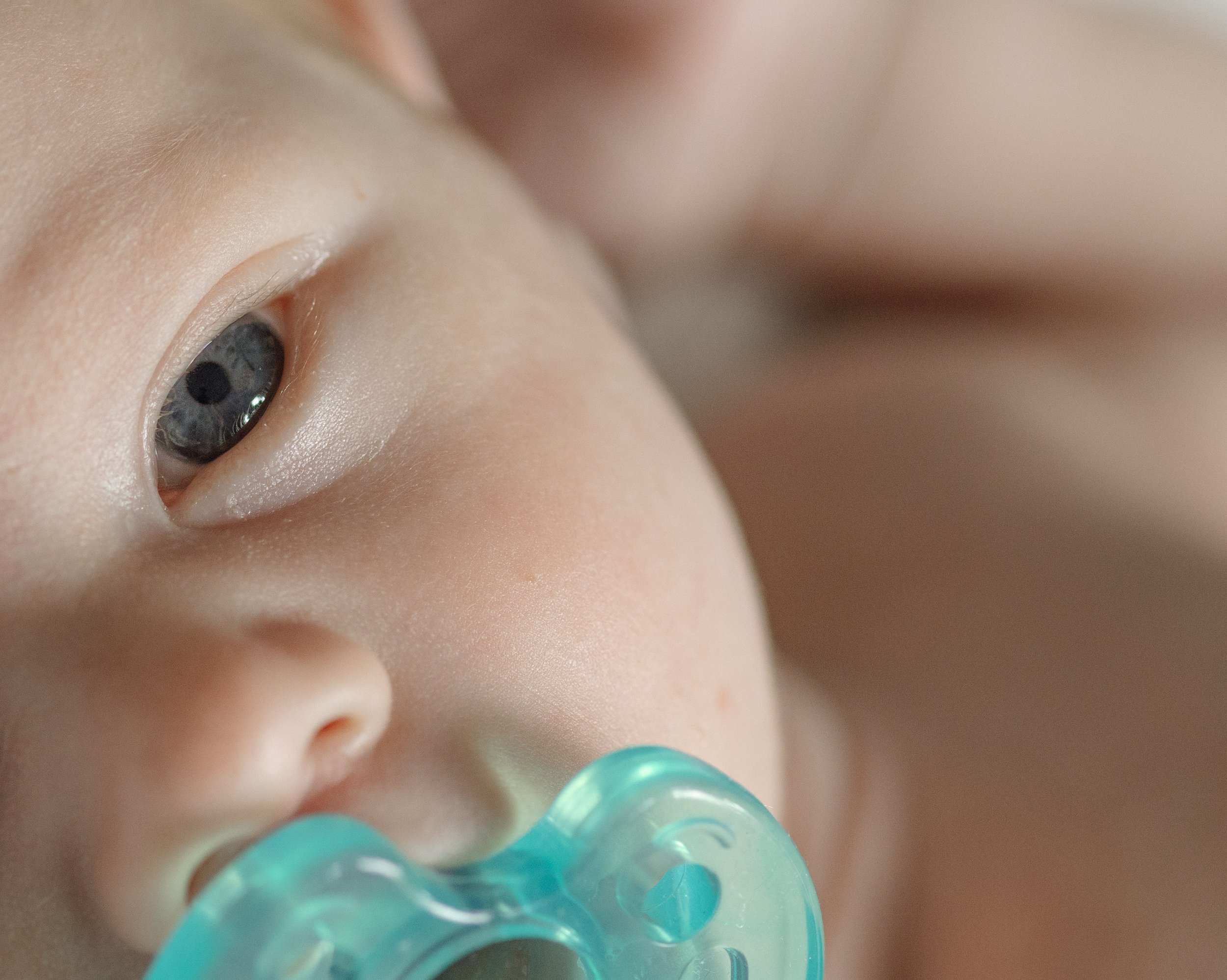 Close-up of a baby’s face, focusing on the eye and surrounding skin. The baby has blue eyes and light skin, with some baby hair visible. newborn photography in dripping springs Texas
