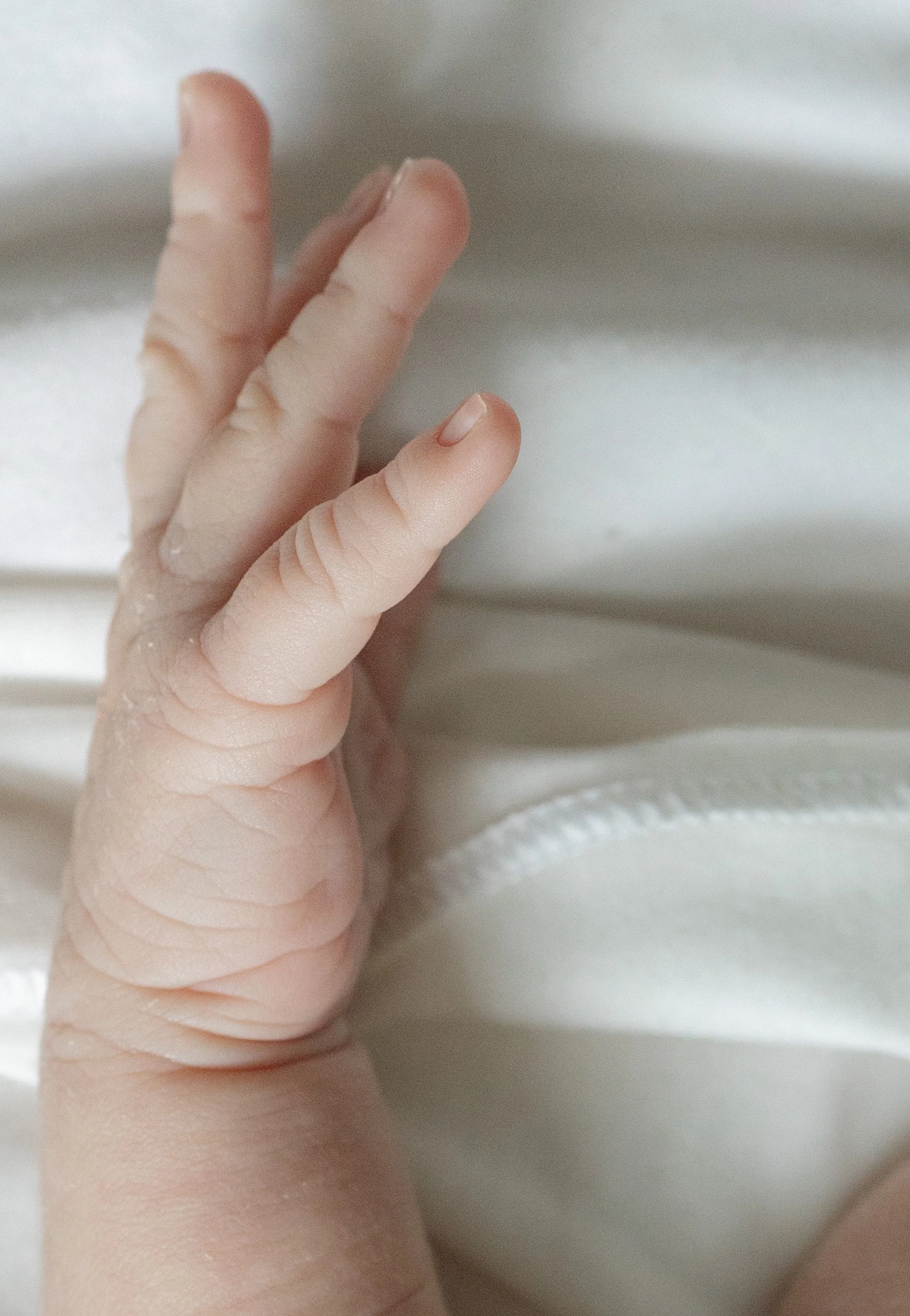 A close-up of a person's hand with three fingers resting on a white surface.