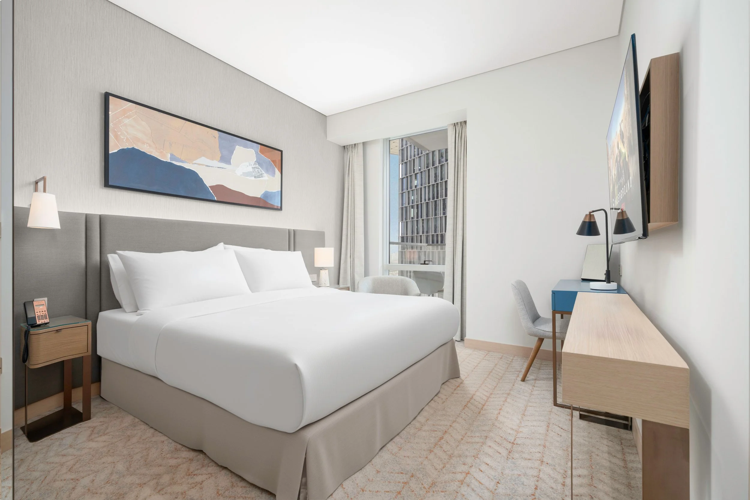 Mid-range 3-star hotel room with a queen bed, work desk, armchair, and city view window