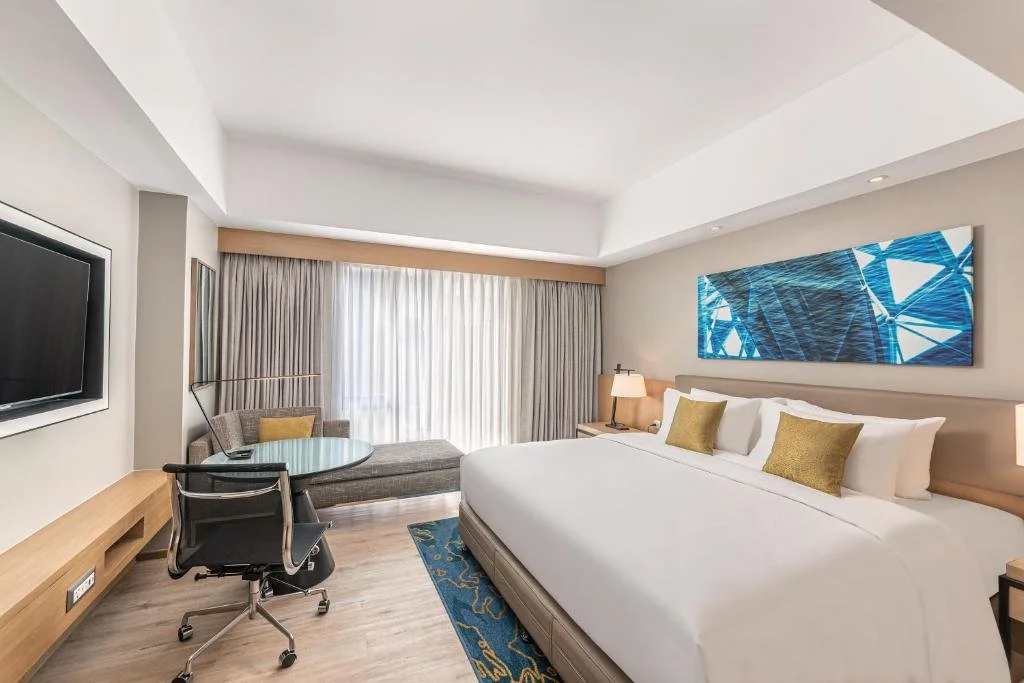 Spacious 4-star hotel room with a king bed, premium linens, seating area, and floor-to-ceiling windows