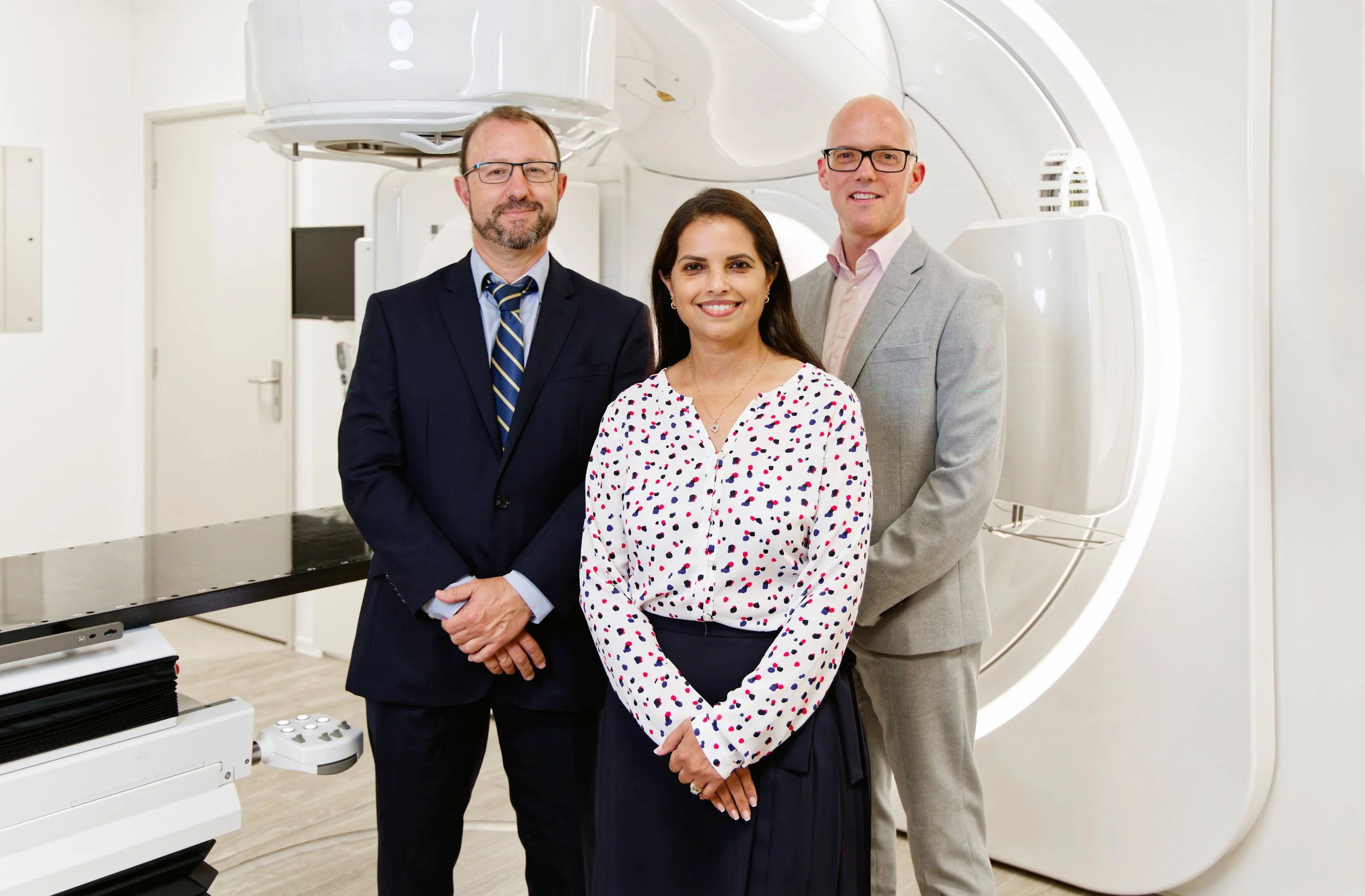 Three doctors posing in a MRI scanner room
